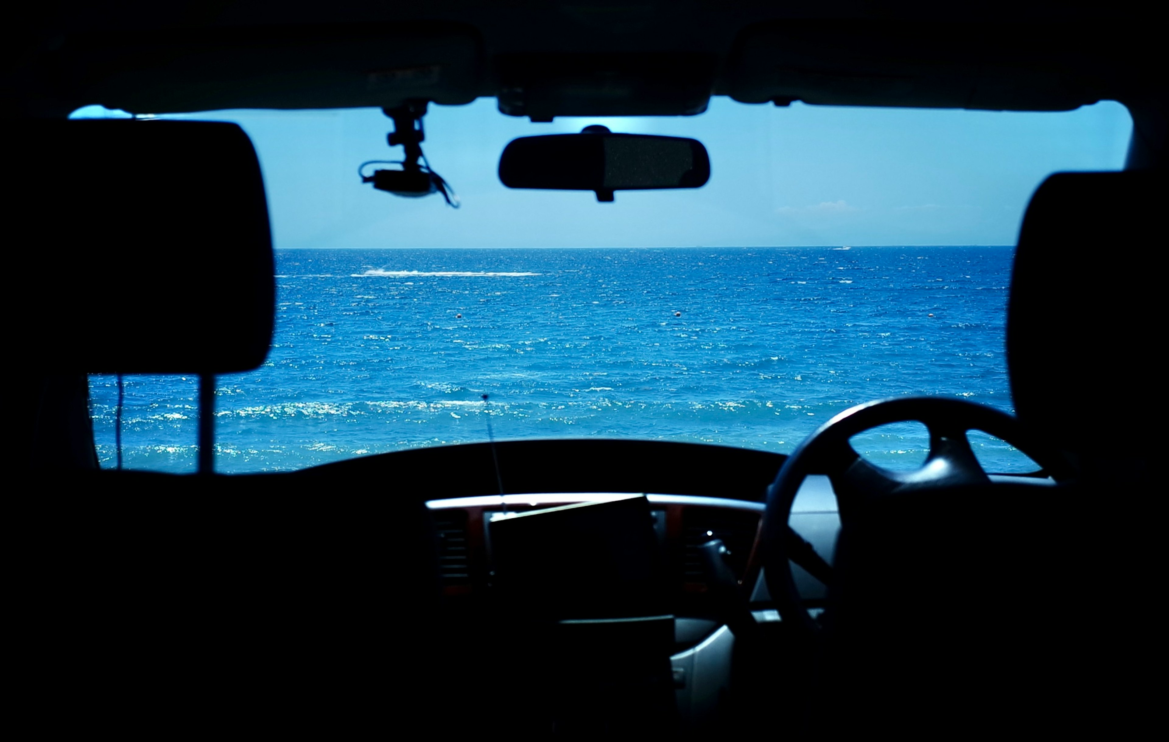 View of the blue ocean from inside a car