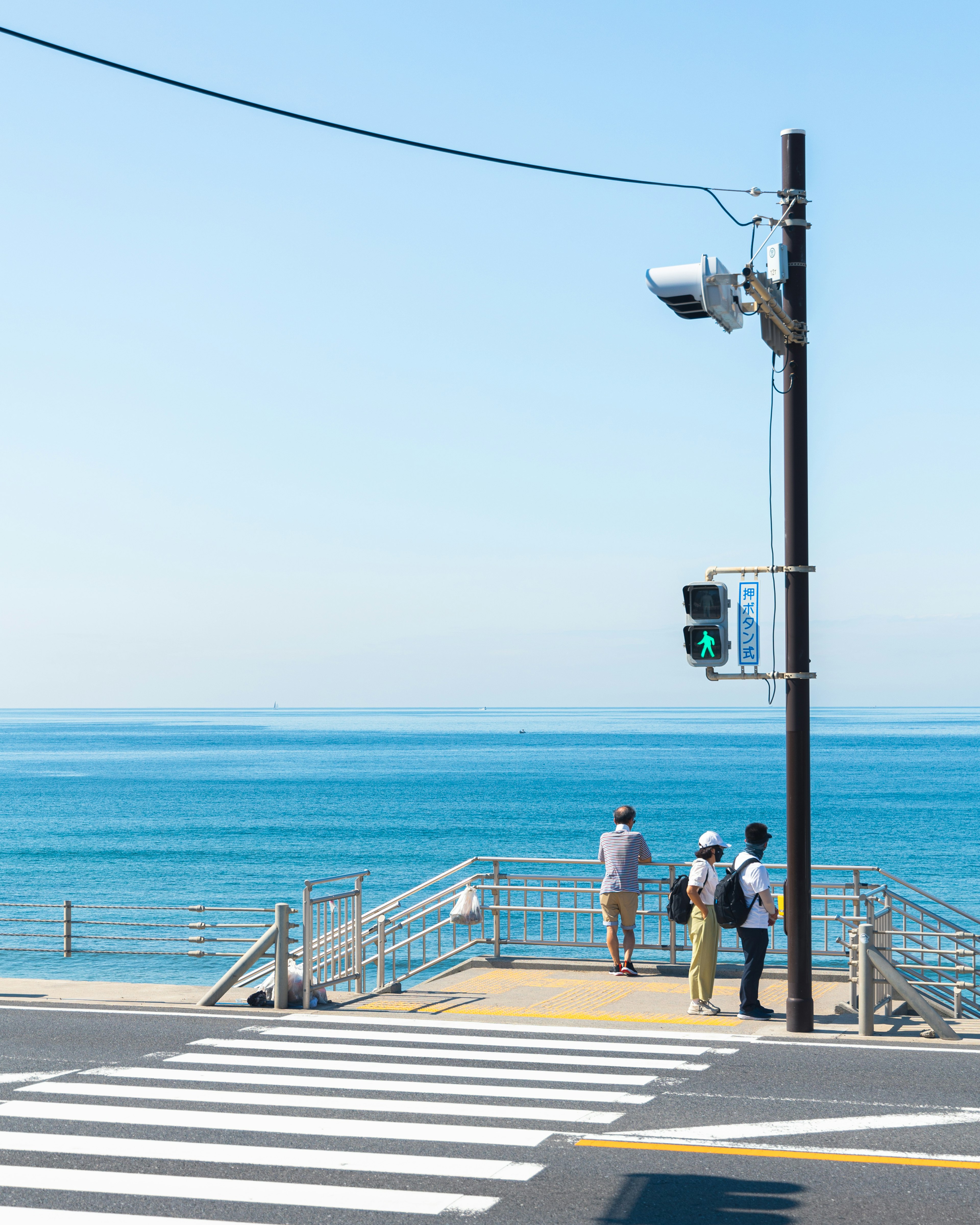 青い海を背景にした人々が信号機の近くに立っている風景