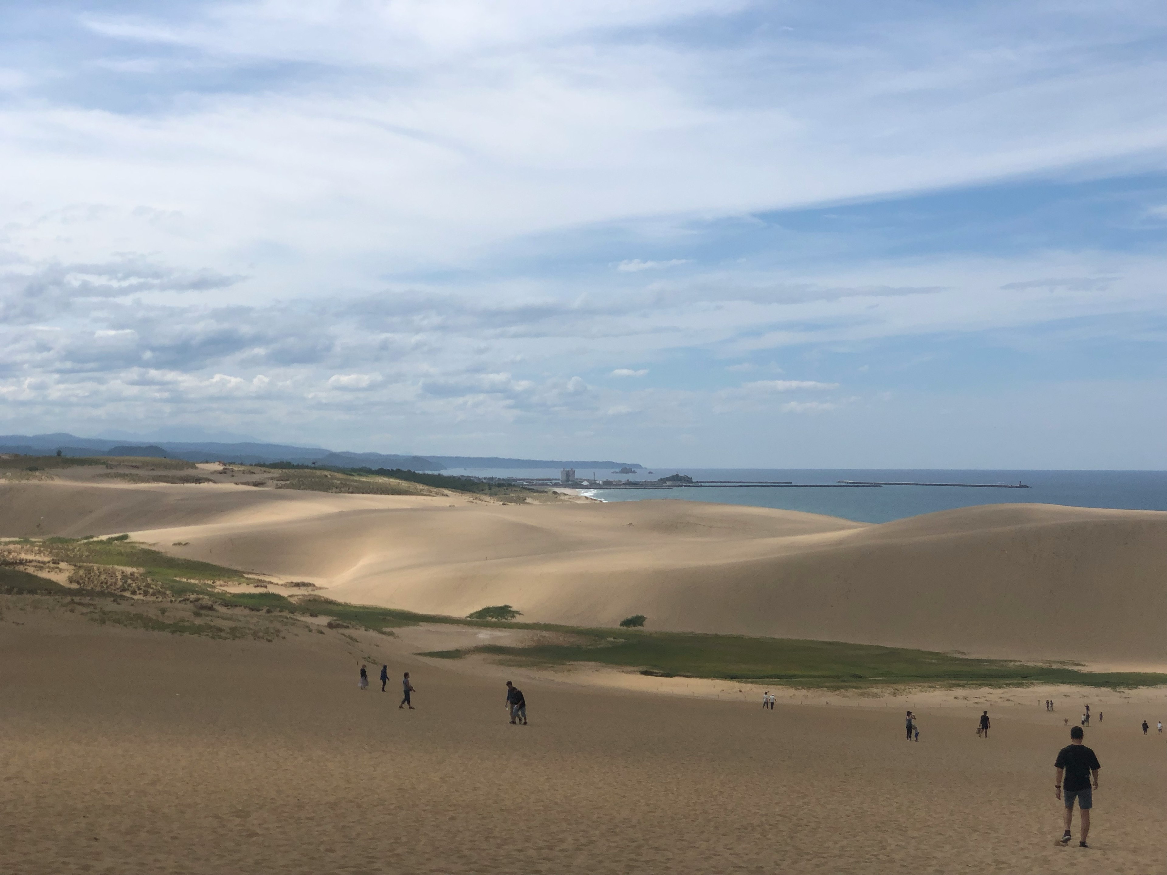 Weite Sanddünen mit Silhouetten von Menschen vor dem Hintergrund des Meeres