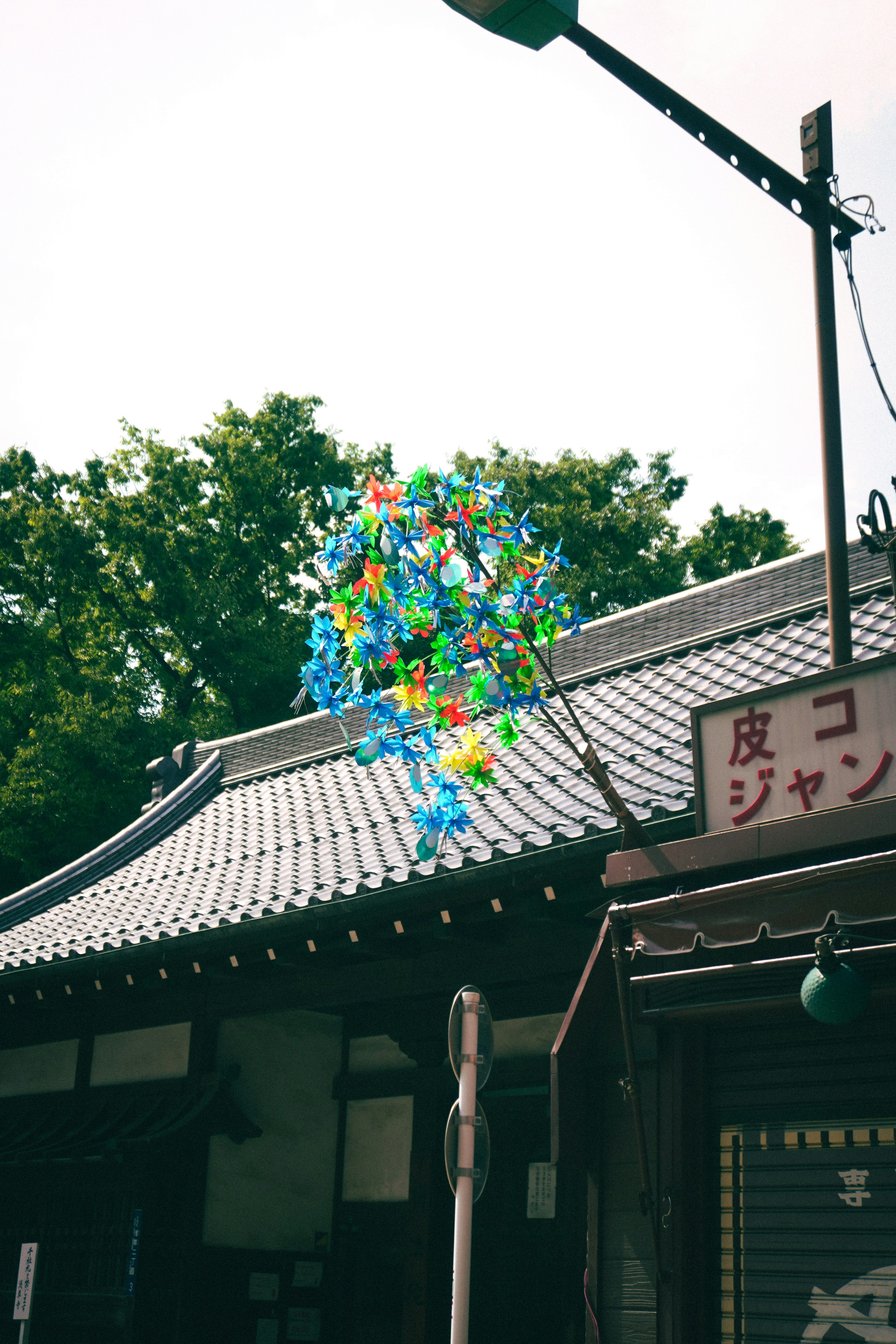 Colorful objects floating above a traditional roof with green trees in the background