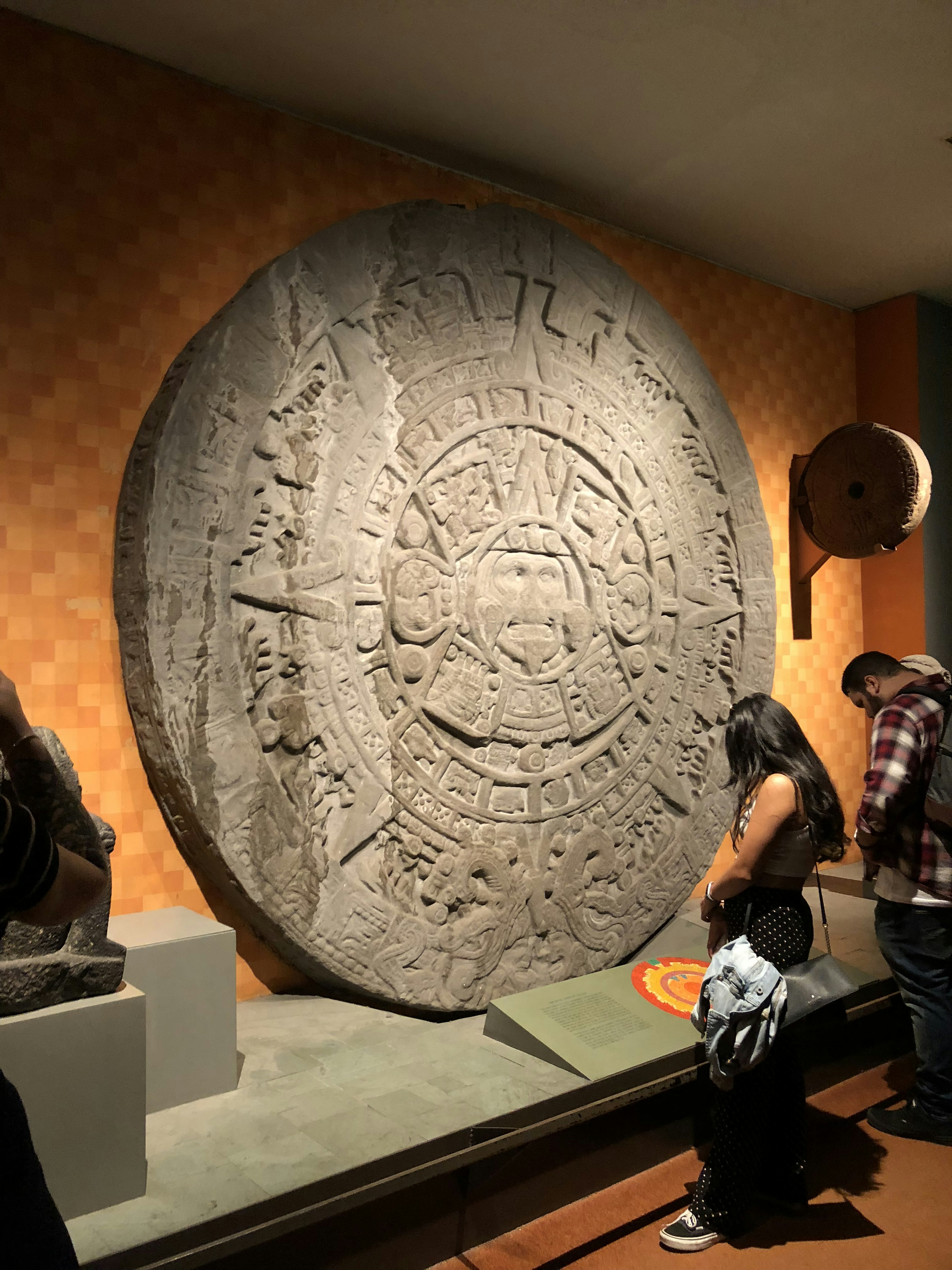 Visitatori che osservano la pietra del sole azteco in un museo