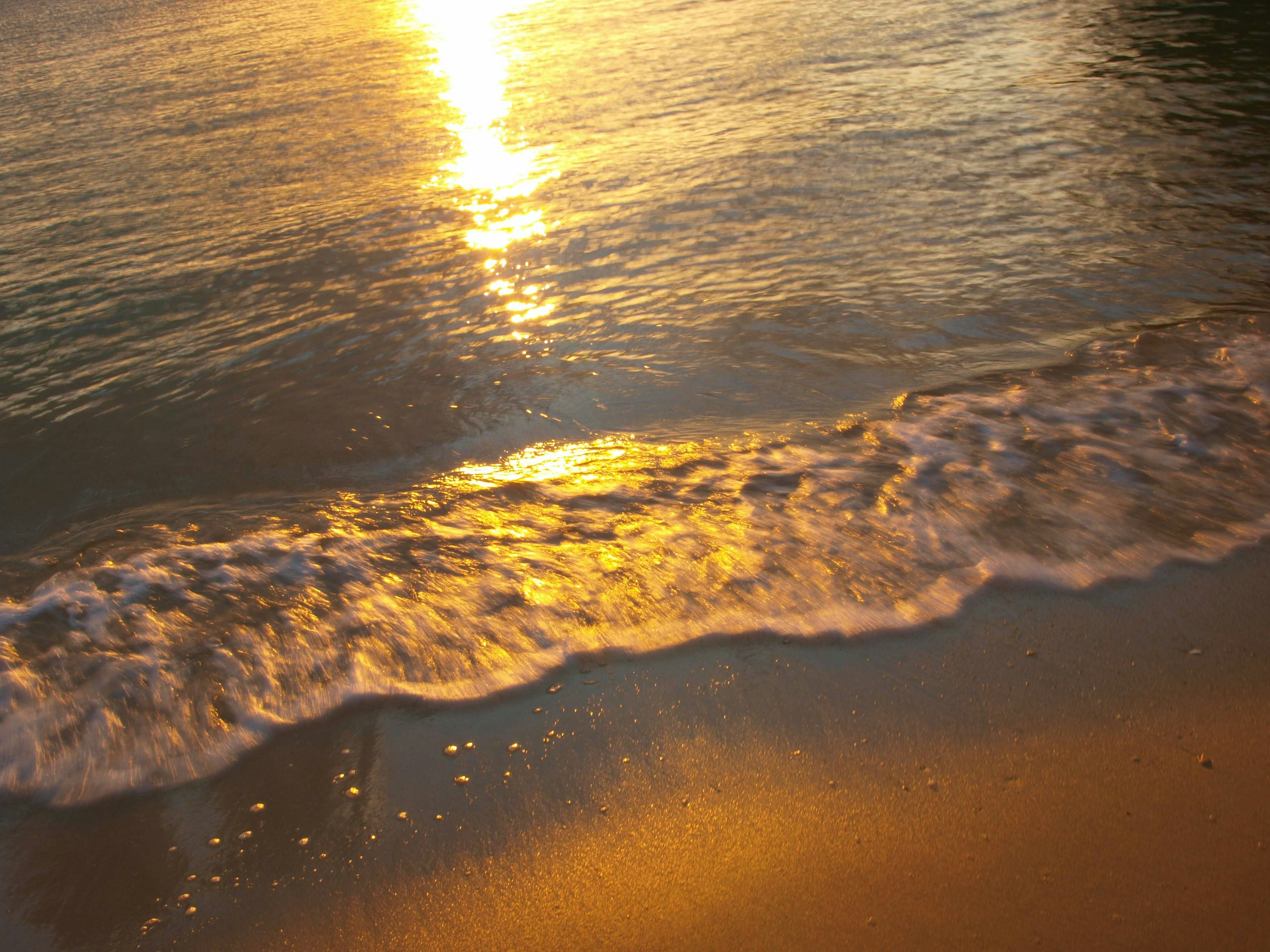 ทิวทัศน์ชายหาดที่สวยงามพร้อมคลื่นและการสะท้อนของพระอาทิตย์ตก