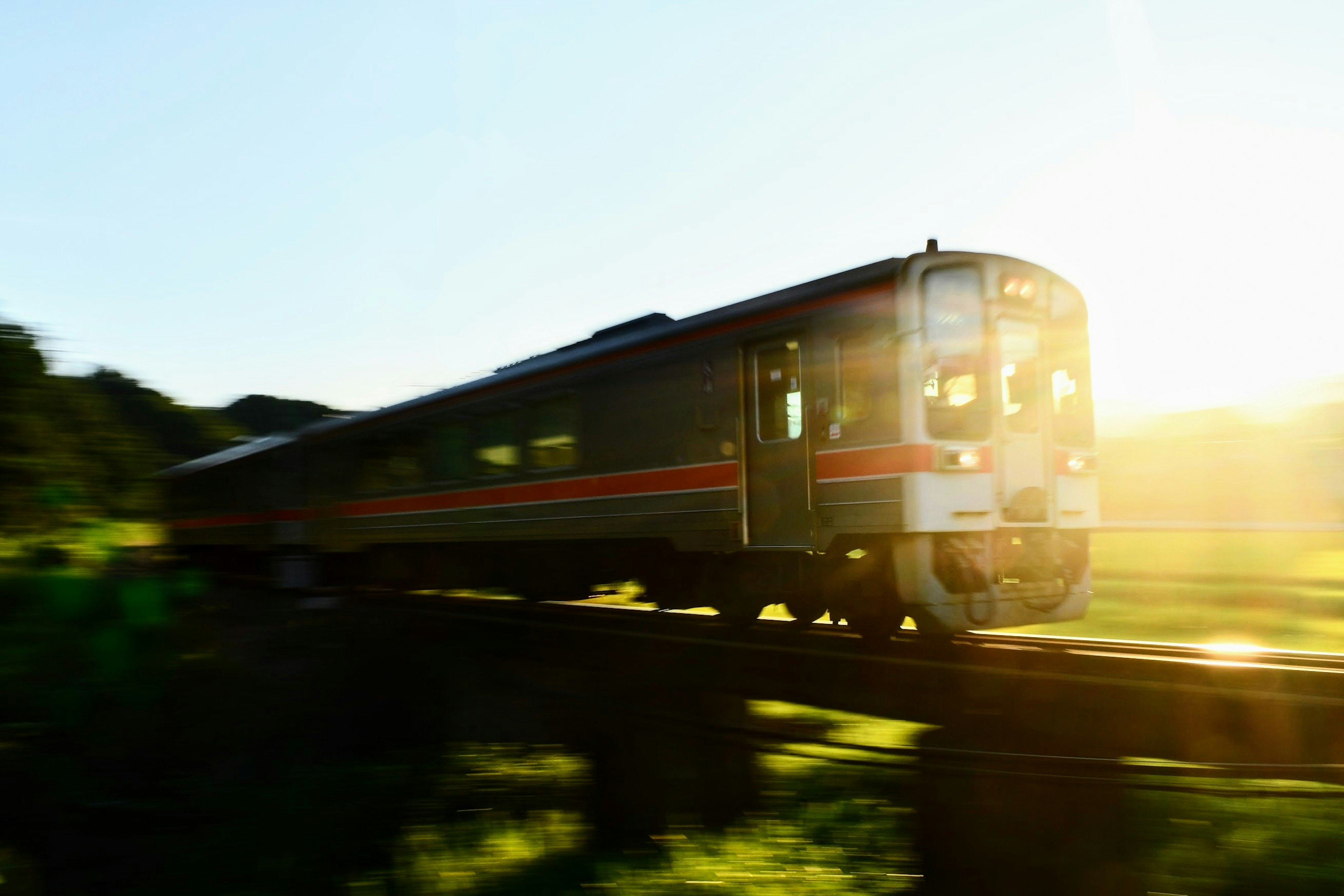 Treno che si muove attraverso un paesaggio verde con il tramonto sullo sfondo