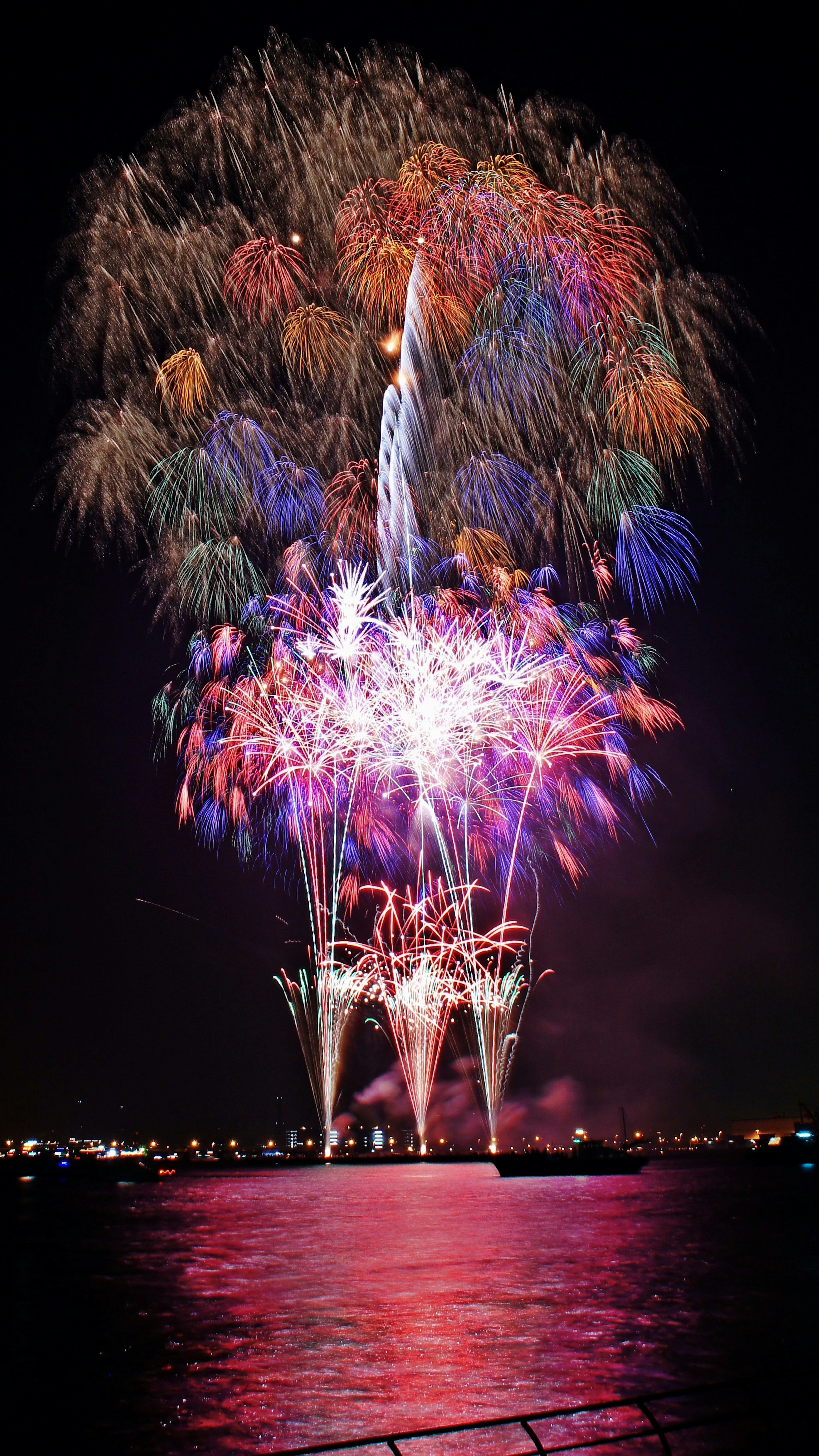 Fuegos artificiales coloridos estallando en el cielo nocturno reflejándose en el agua