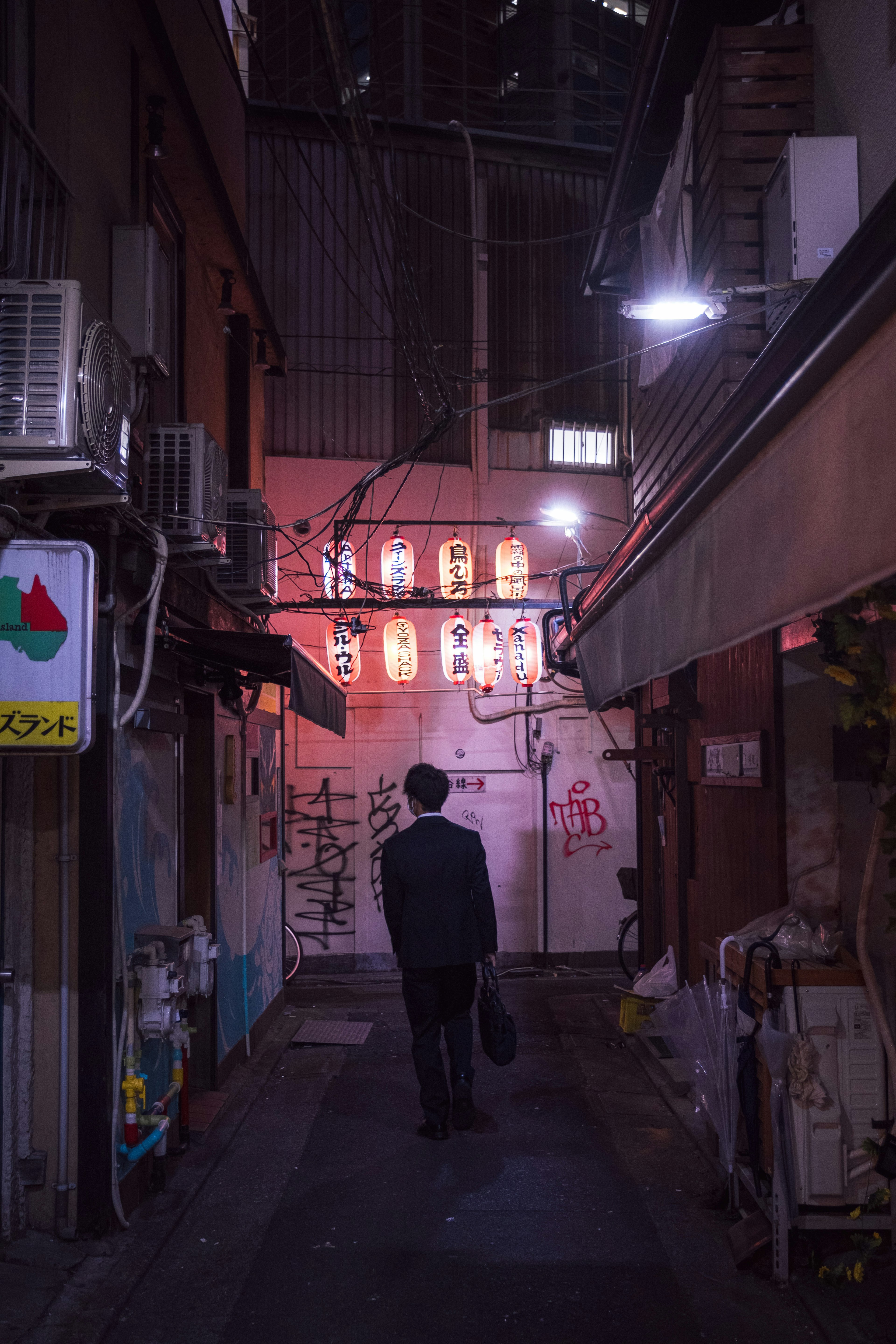 Un homme marchant dans une ruelle sombre avec des fenêtres illuminées