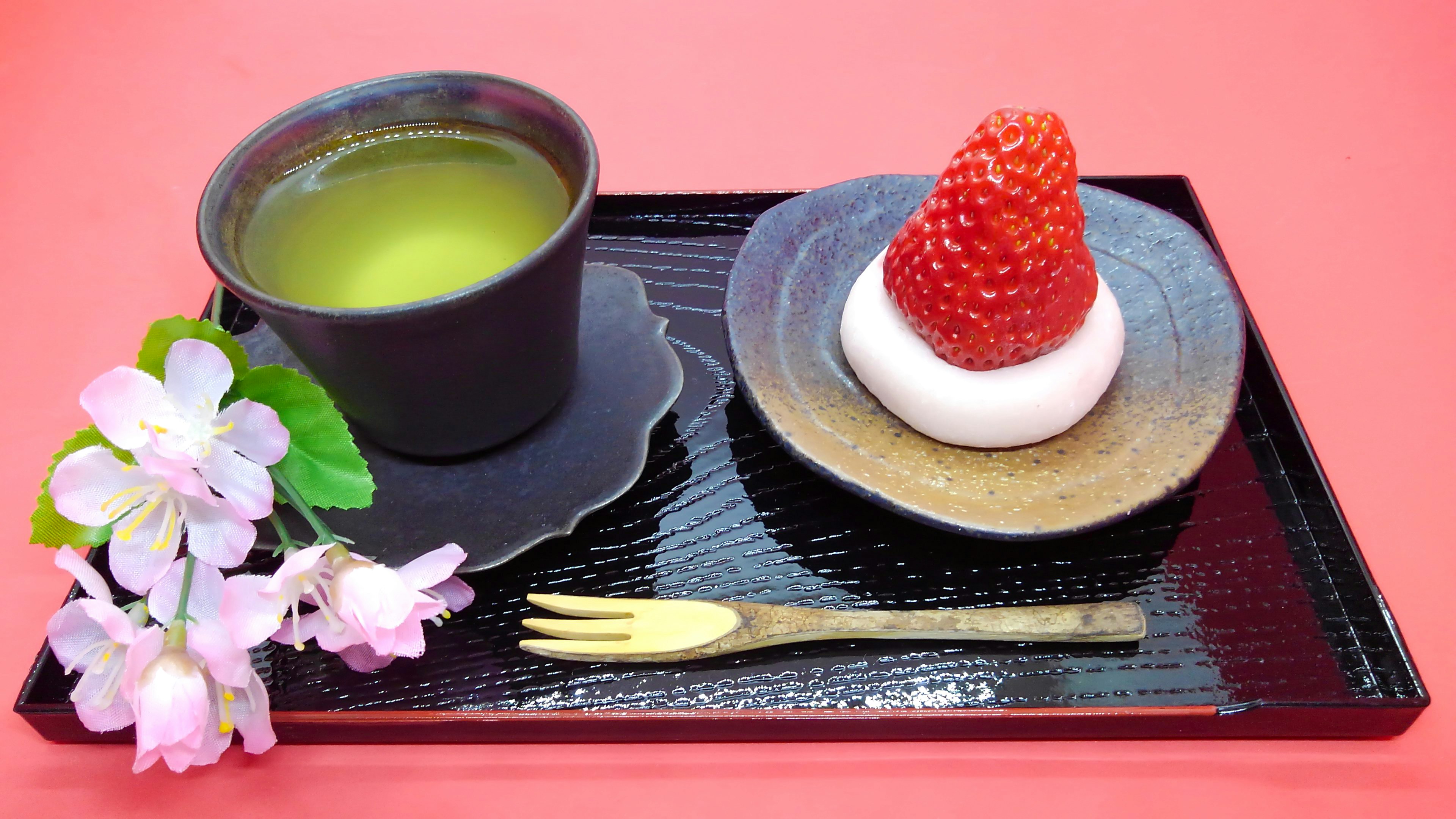 Dessert avec du thé vert et du mochi à la fraise sur une assiette noire