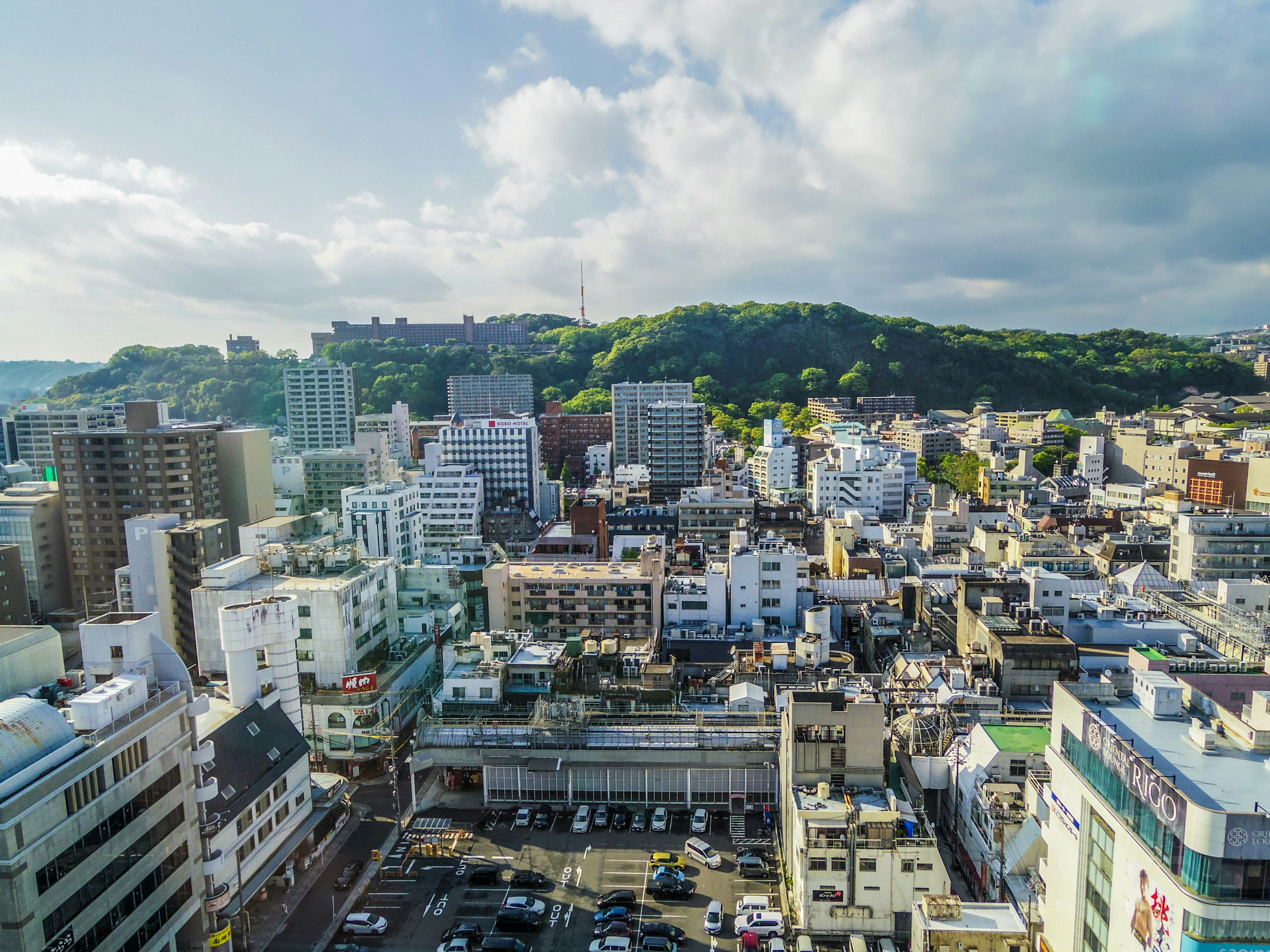 Panoramic view of a city featuring high-rise buildings and green hills