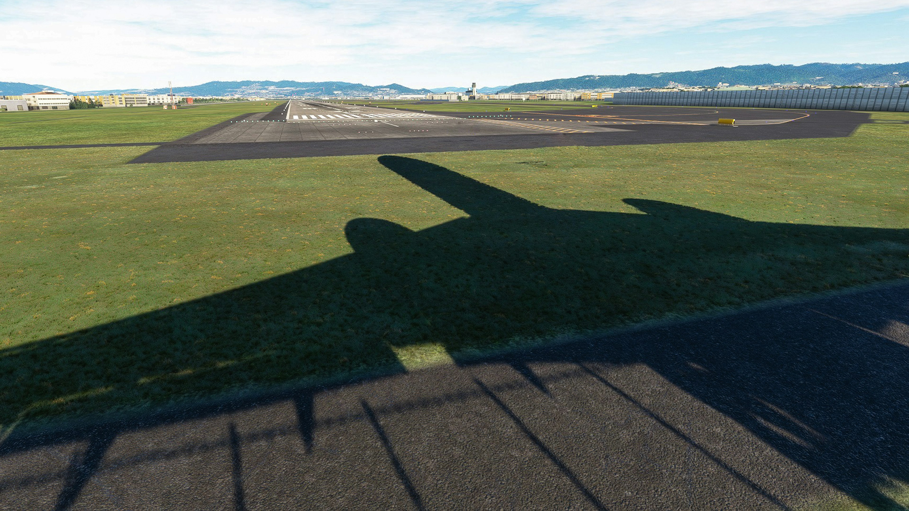 Schatten eines Flugzeugs auf der Landebahn mit umliegender Landschaft