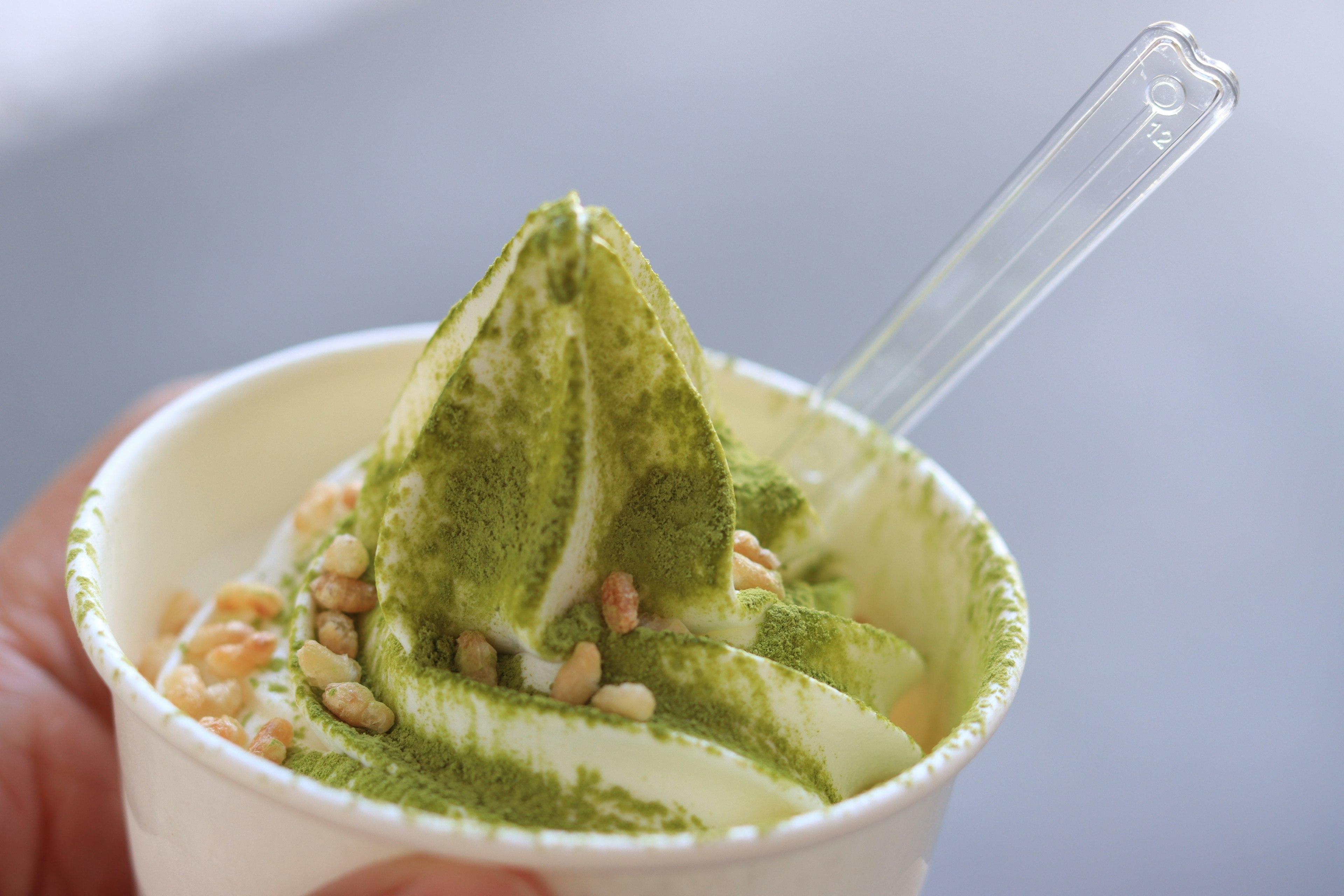 Cup of matcha soft serve ice cream topped with rice crisps