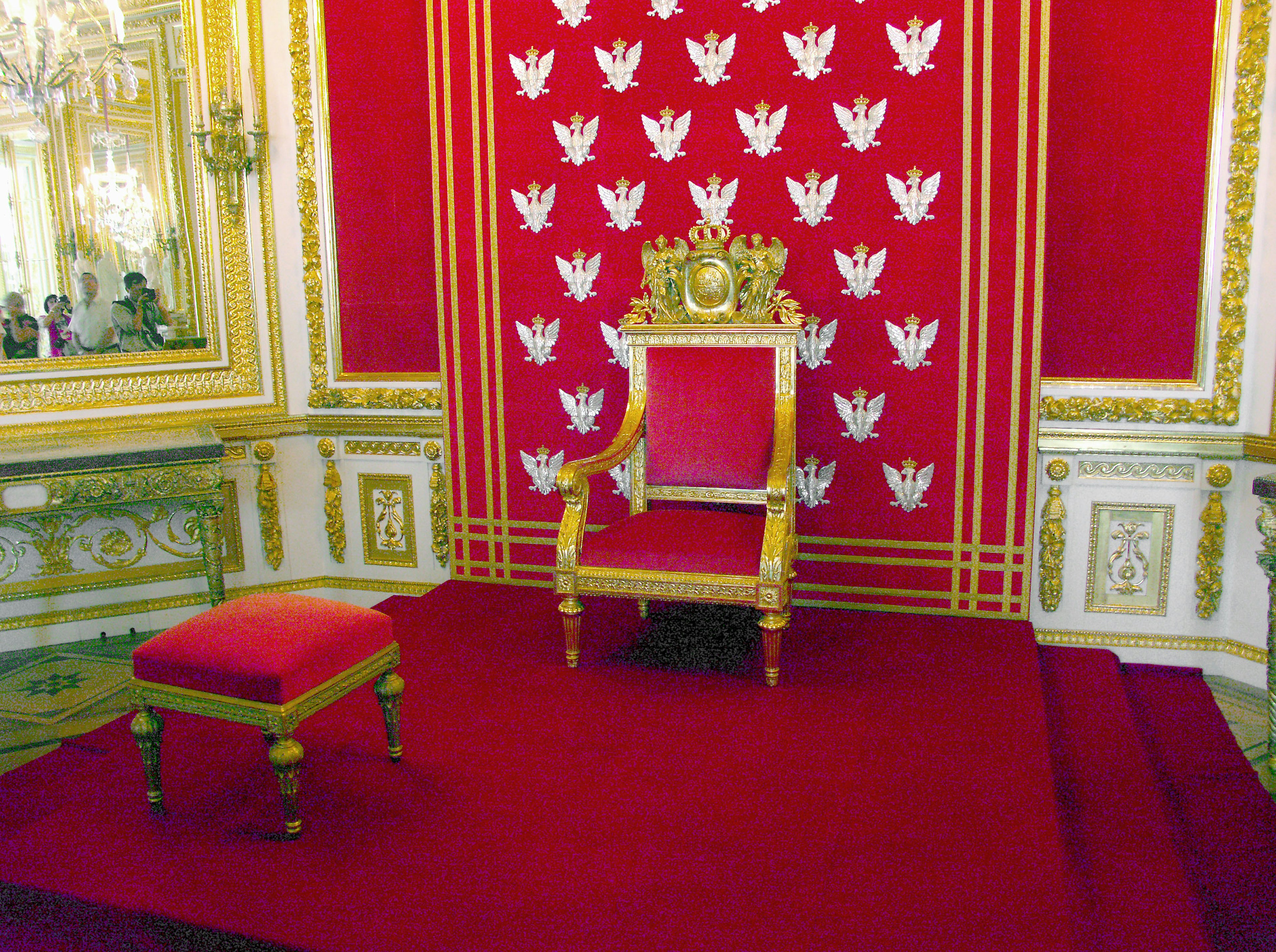 Luxurious throne and ottoman with a red backdrop and golden decorations