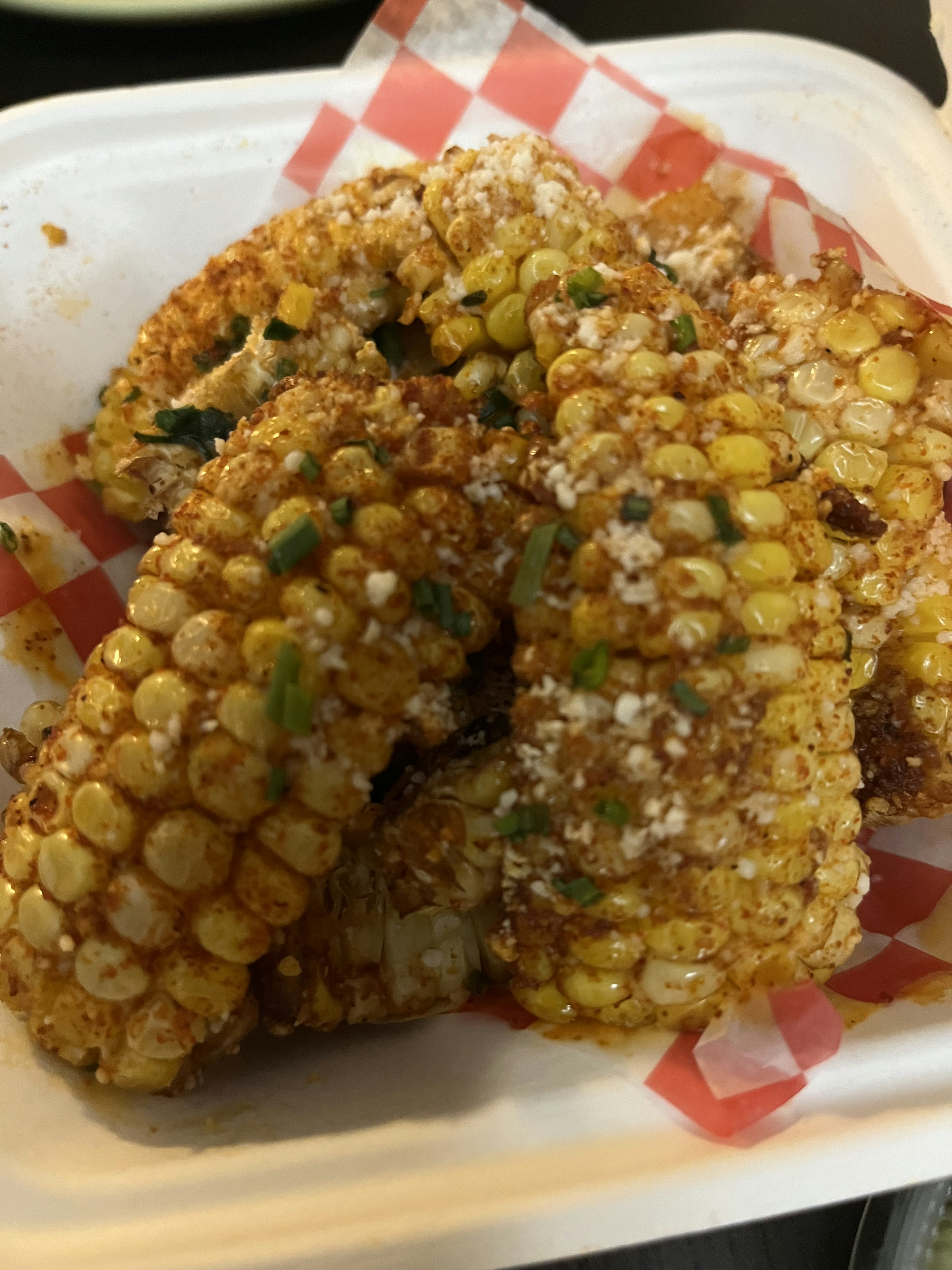 Image of grilled corn served on a white plate with toppings