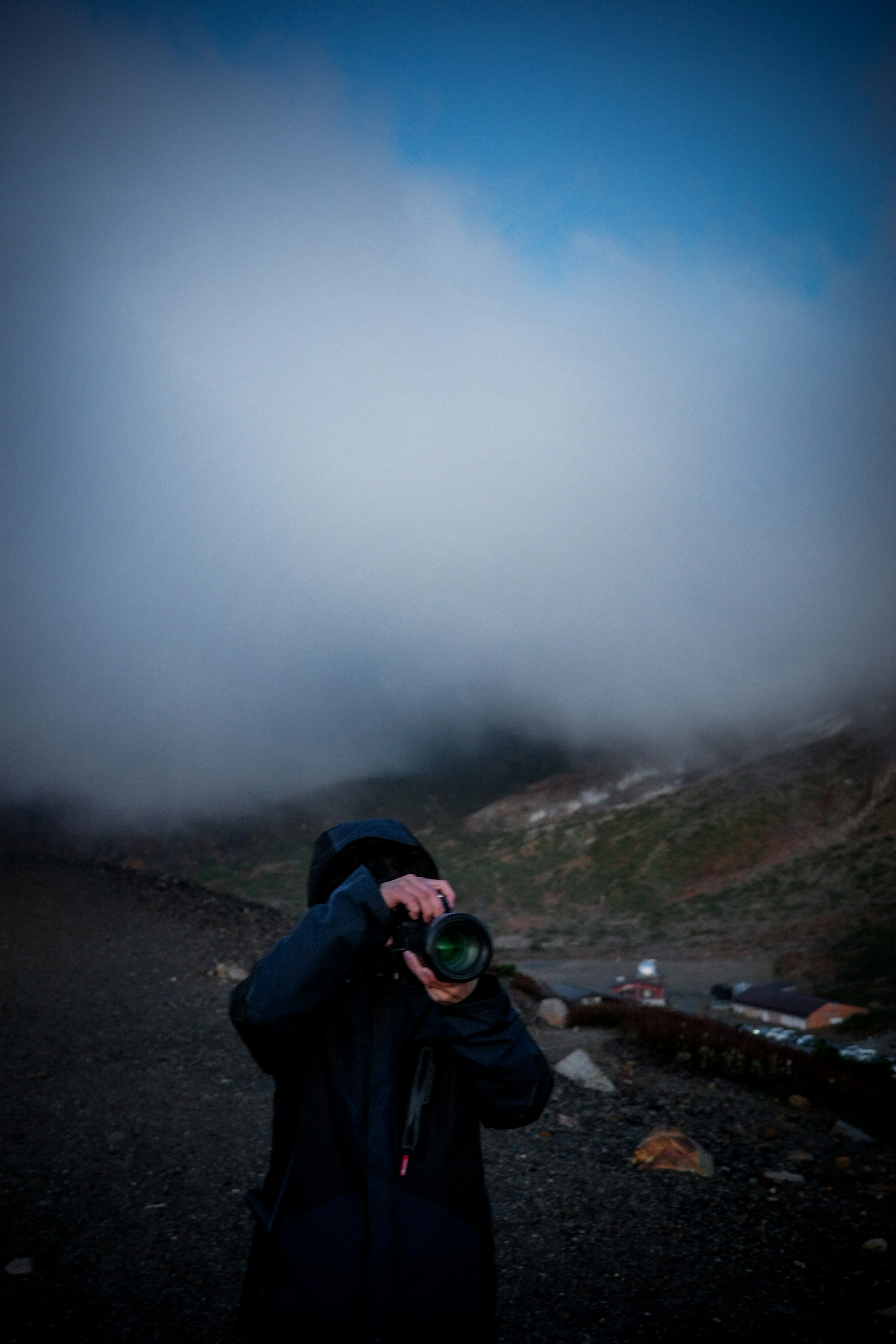 Silhouette of a person holding a camera in fog