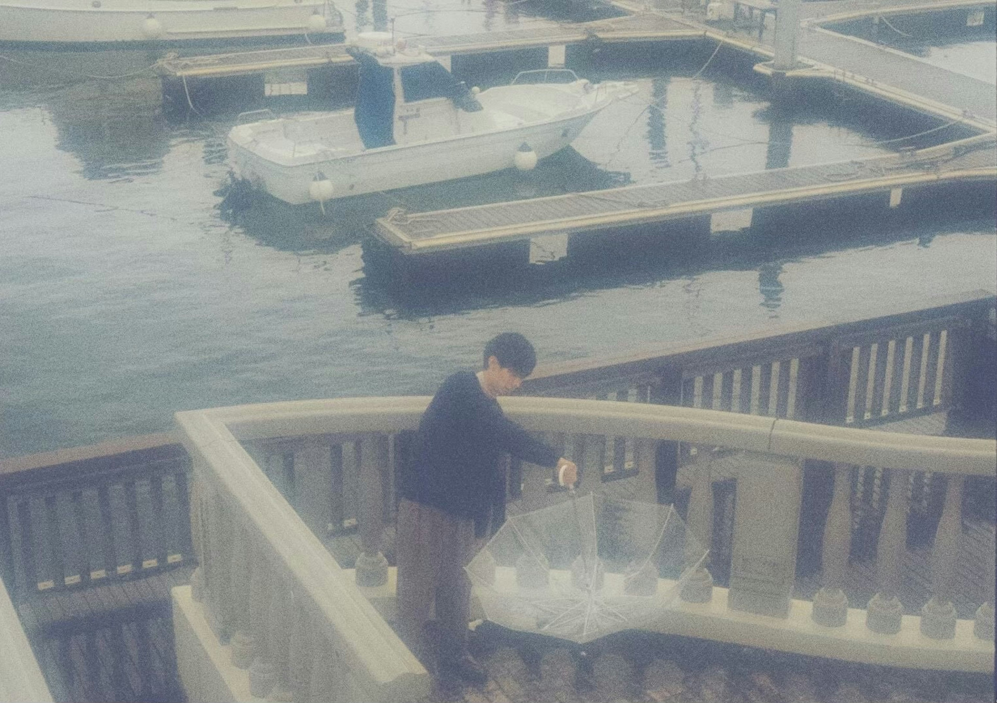 Ein Mann mit einem Regenschirm, der Treppen am Wasser hinuntergeht