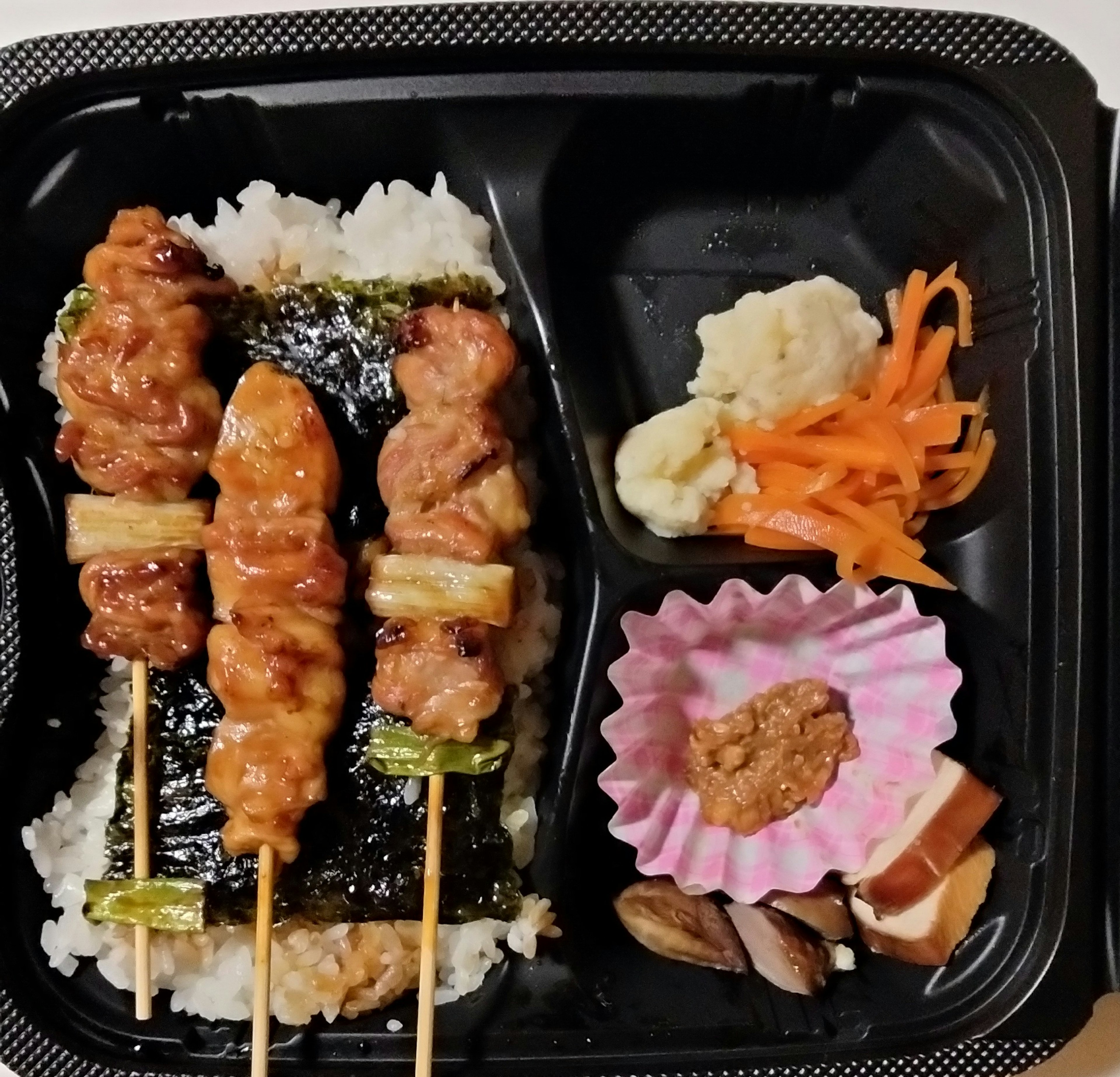 Image of a bento box featuring grilled chicken skewers and rice