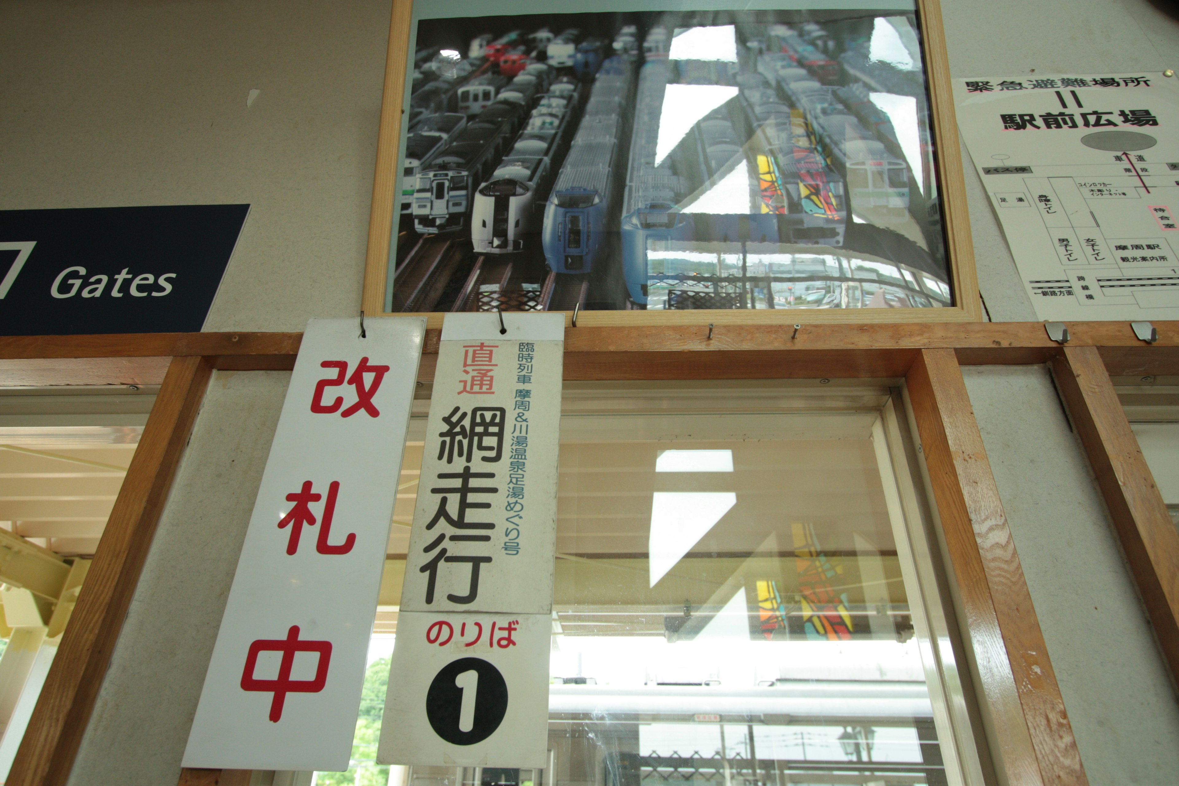 Interior of a train station showing signs and an image of trains