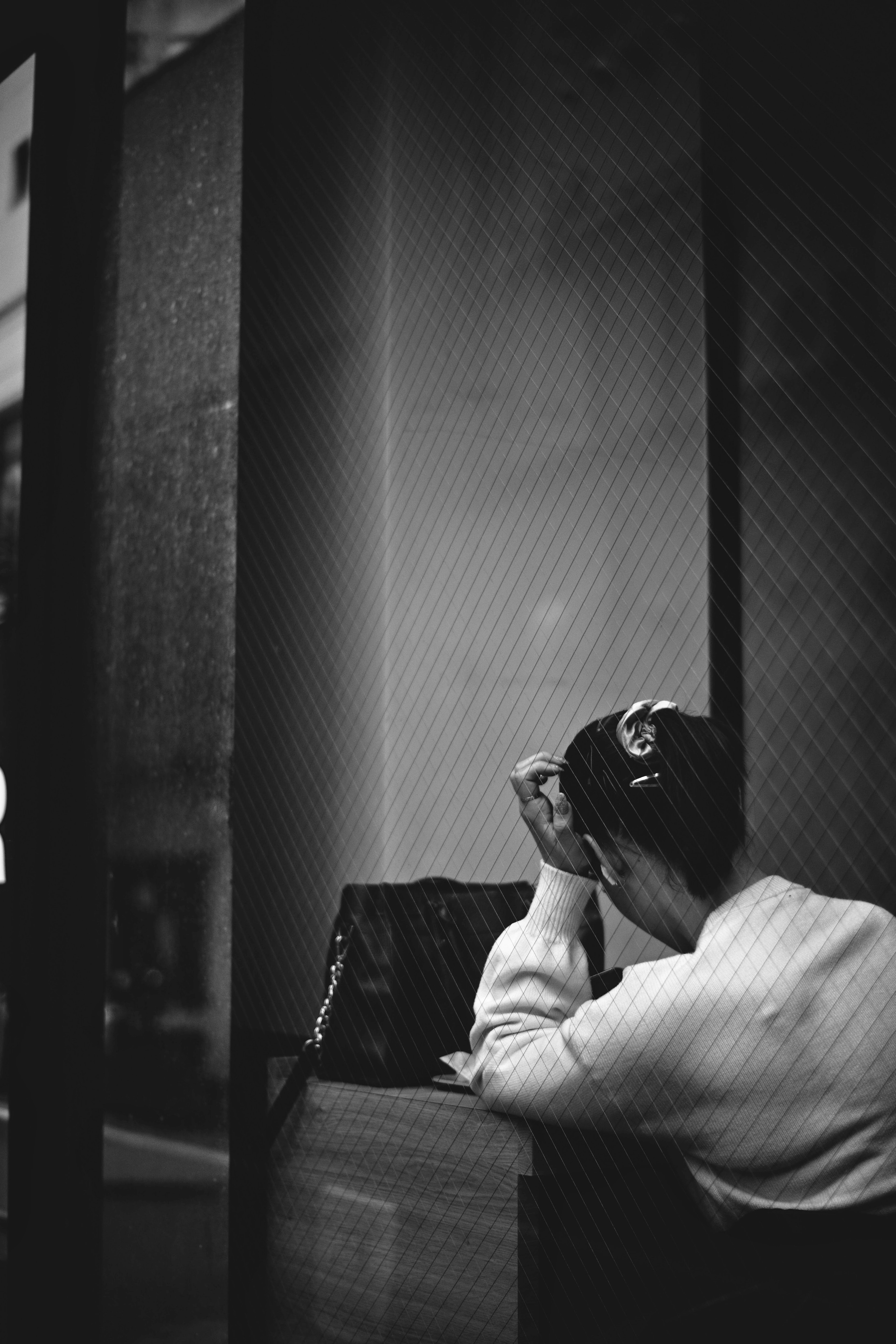 Black and white photo of a person sitting by a window with their head in their hands