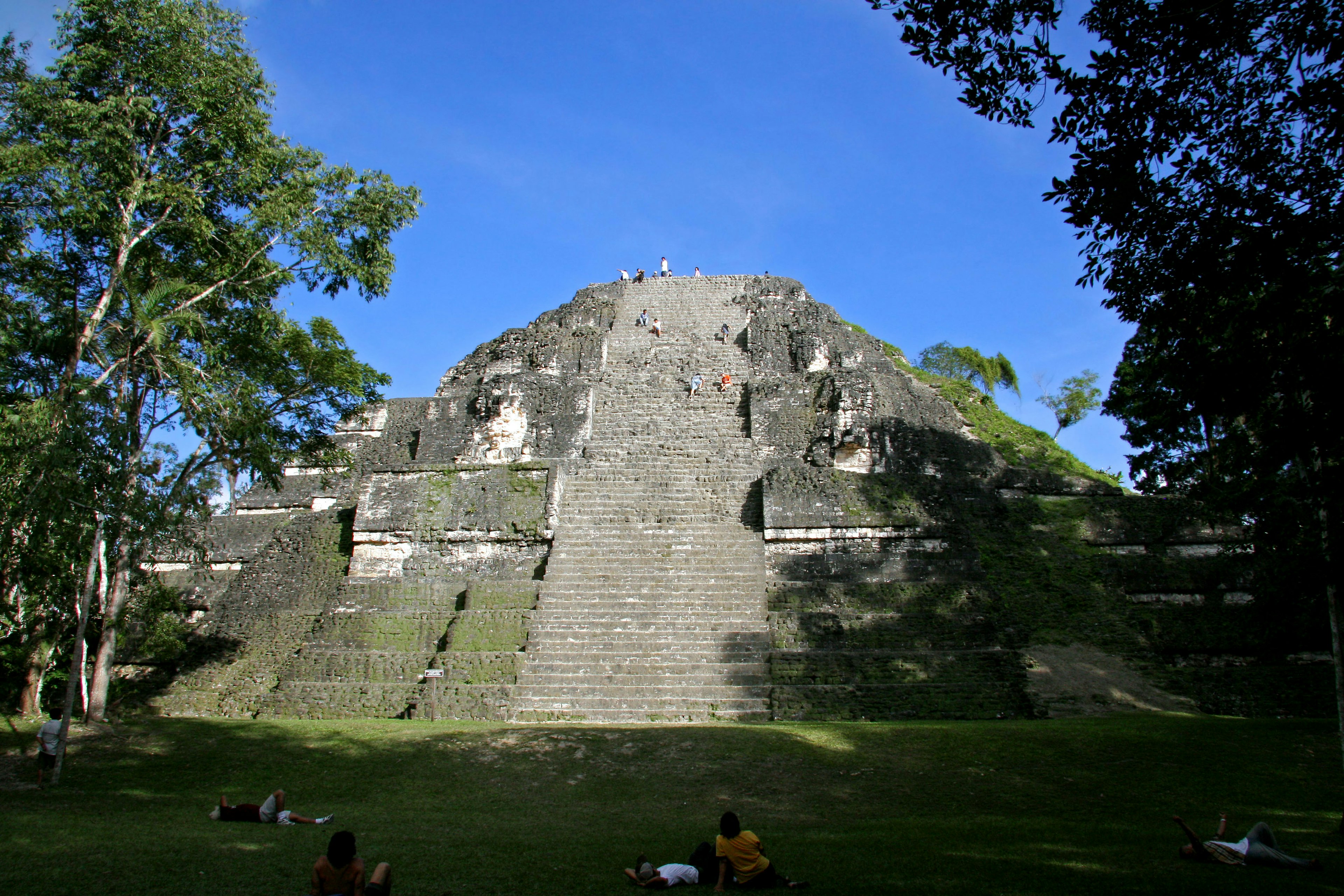 Ancient Mayan pyramid with steps under a blue sky and green trees