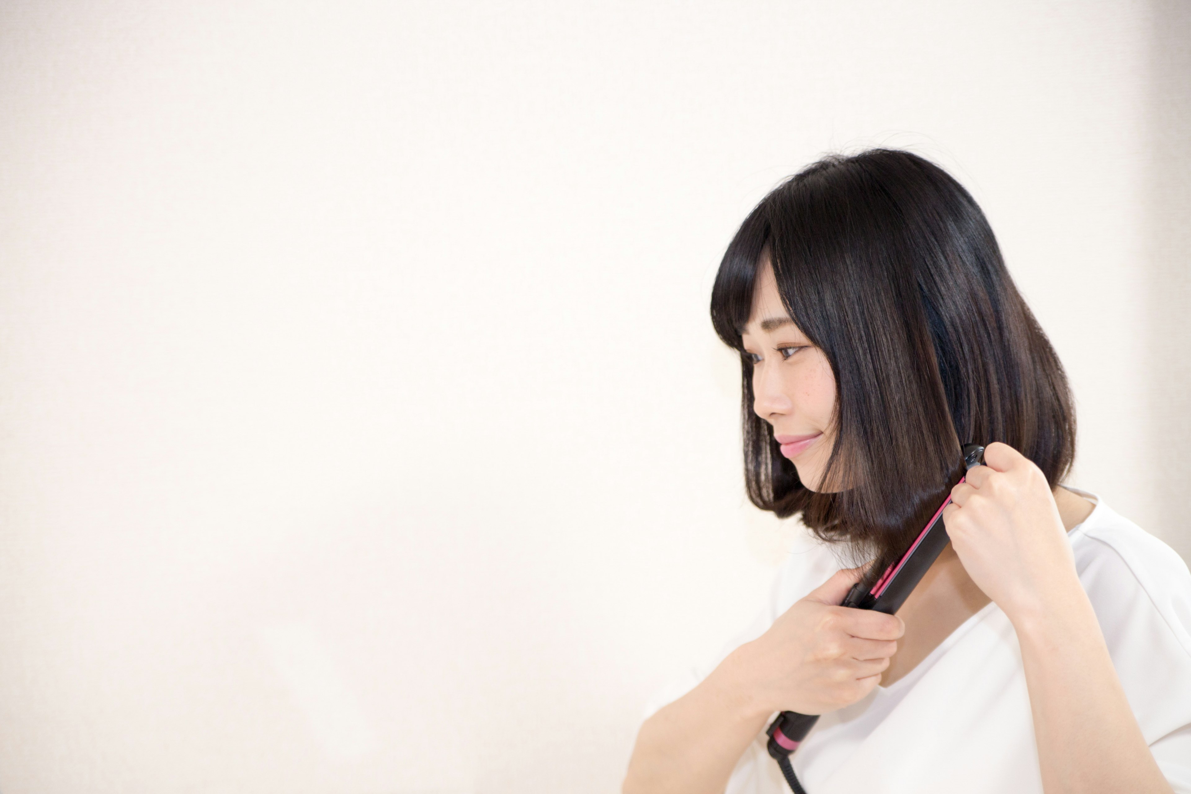 Una mujer alisando su cabello con una plancha