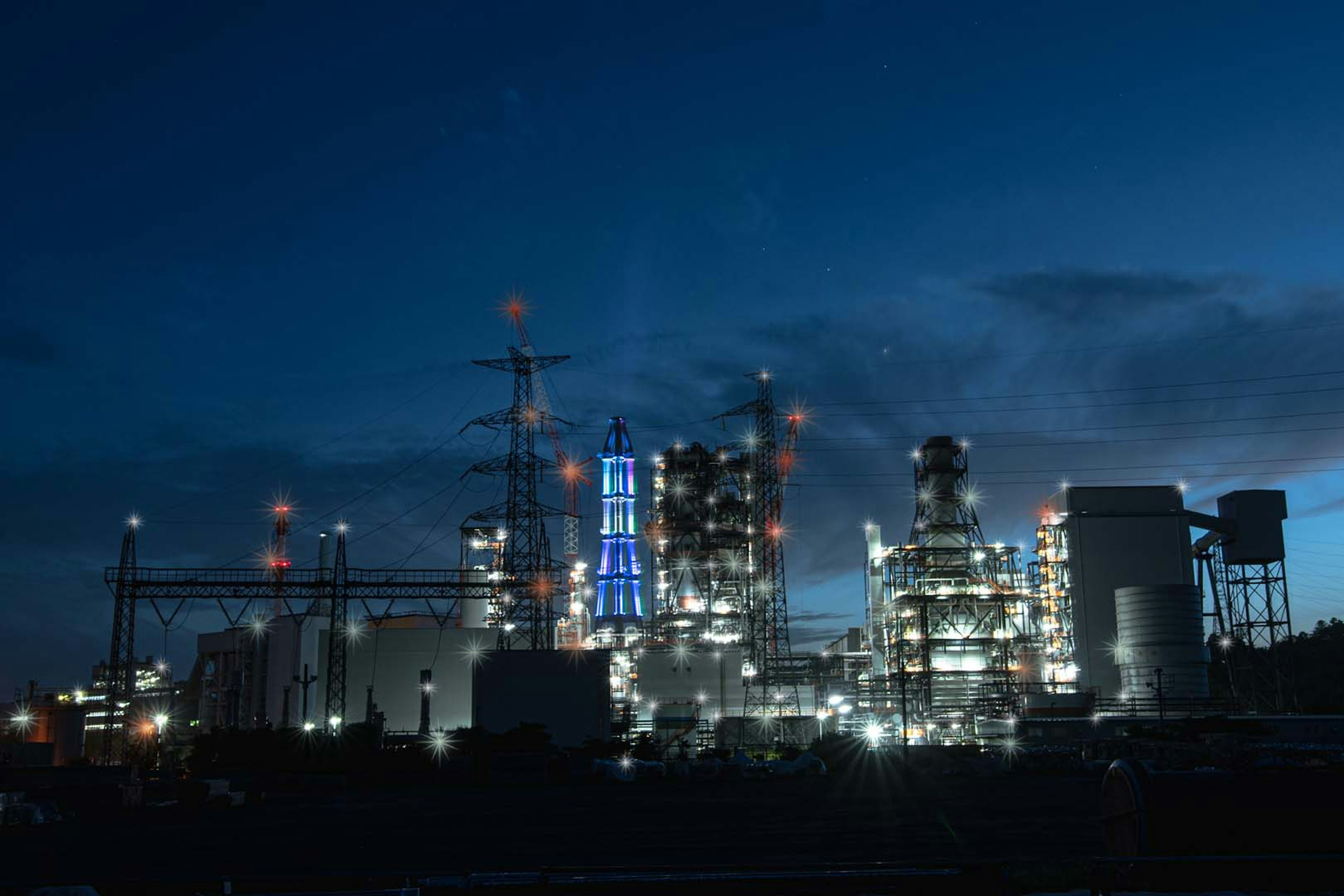 Industrial complex illuminated at night with smokestacks and buildings