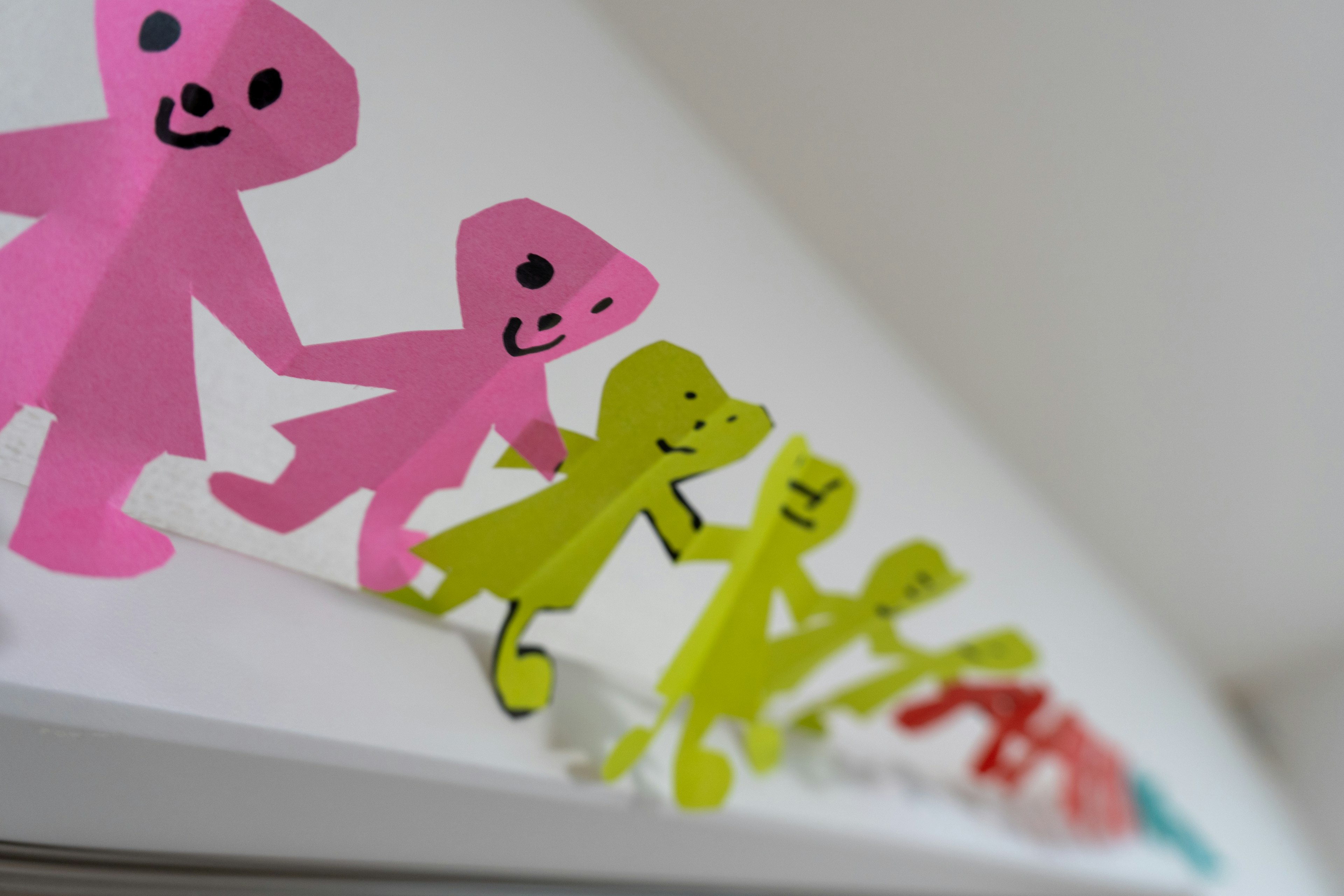 Colorful paper dolls lined up featuring pink, green, and red colors