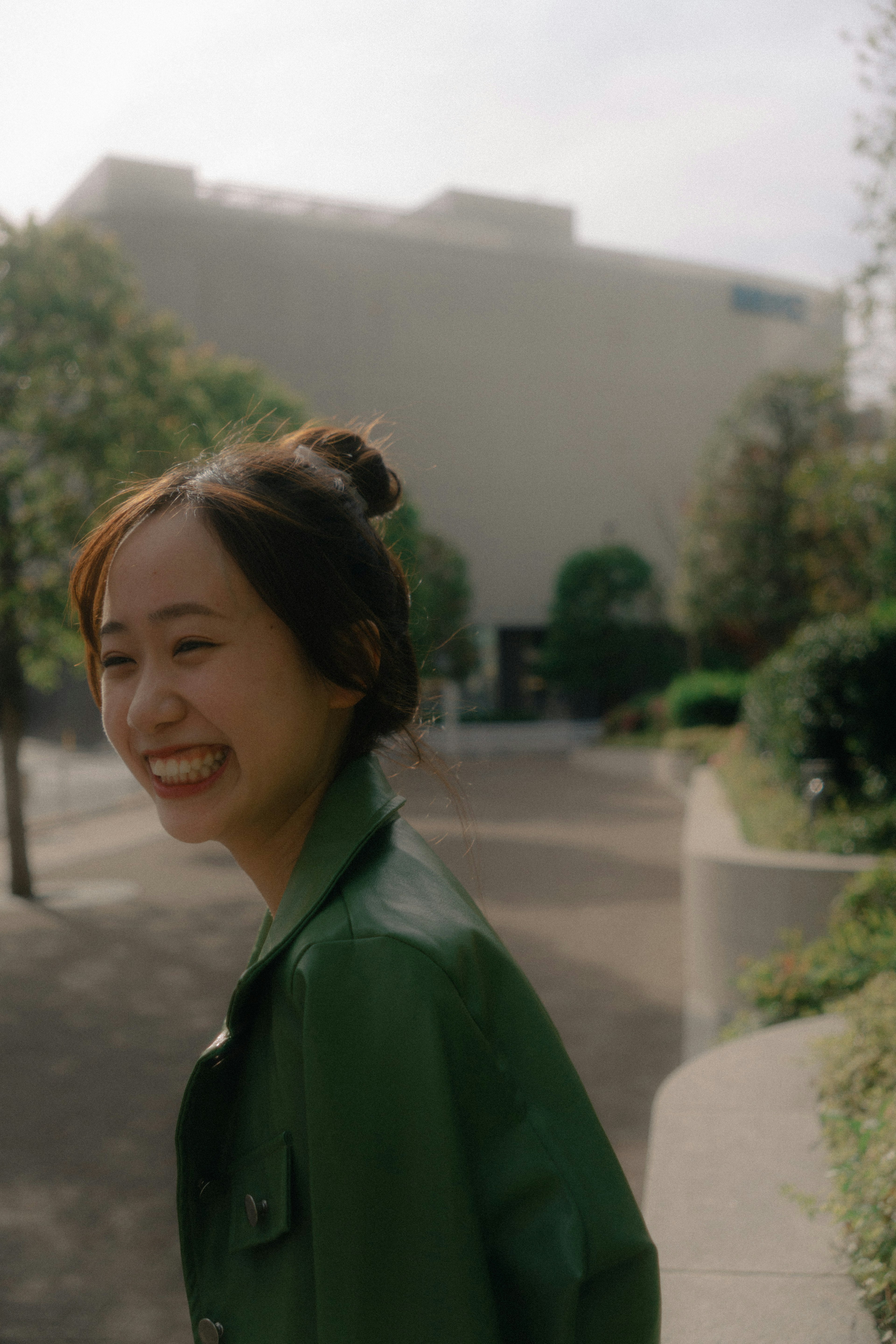 Femme souriante en veste verte dans un paysage urbain