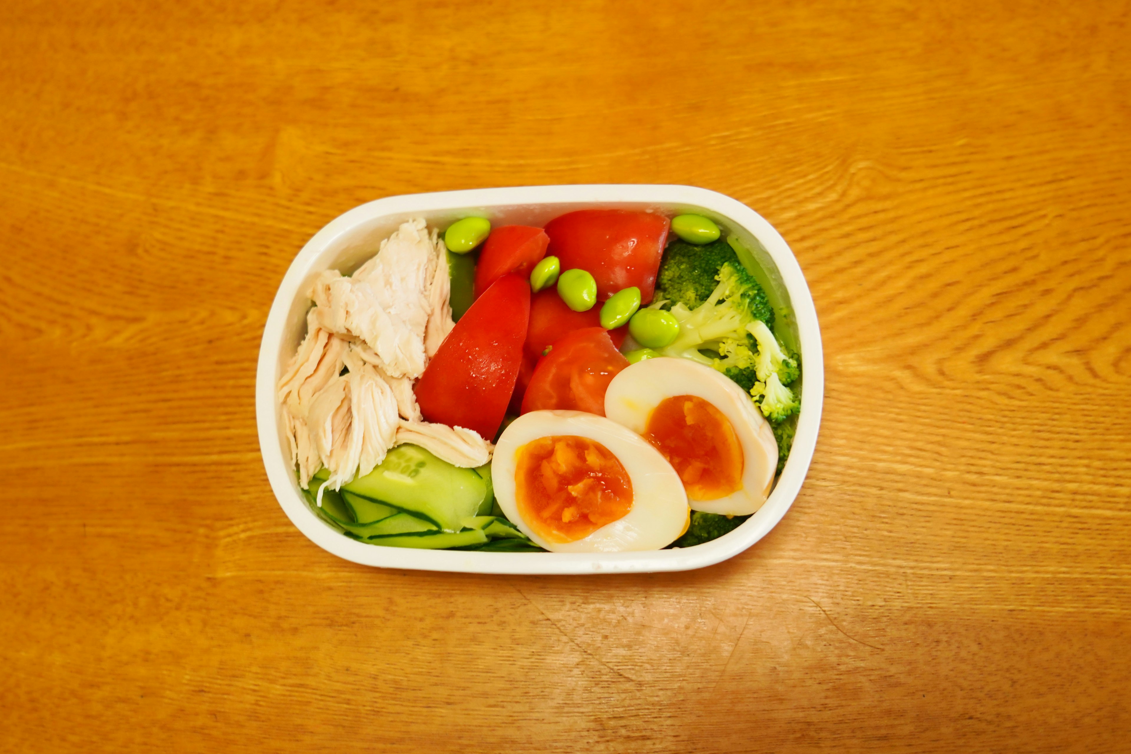 Salad bowl featuring sliced chicken, tomatoes, eggs, and assorted vegetables