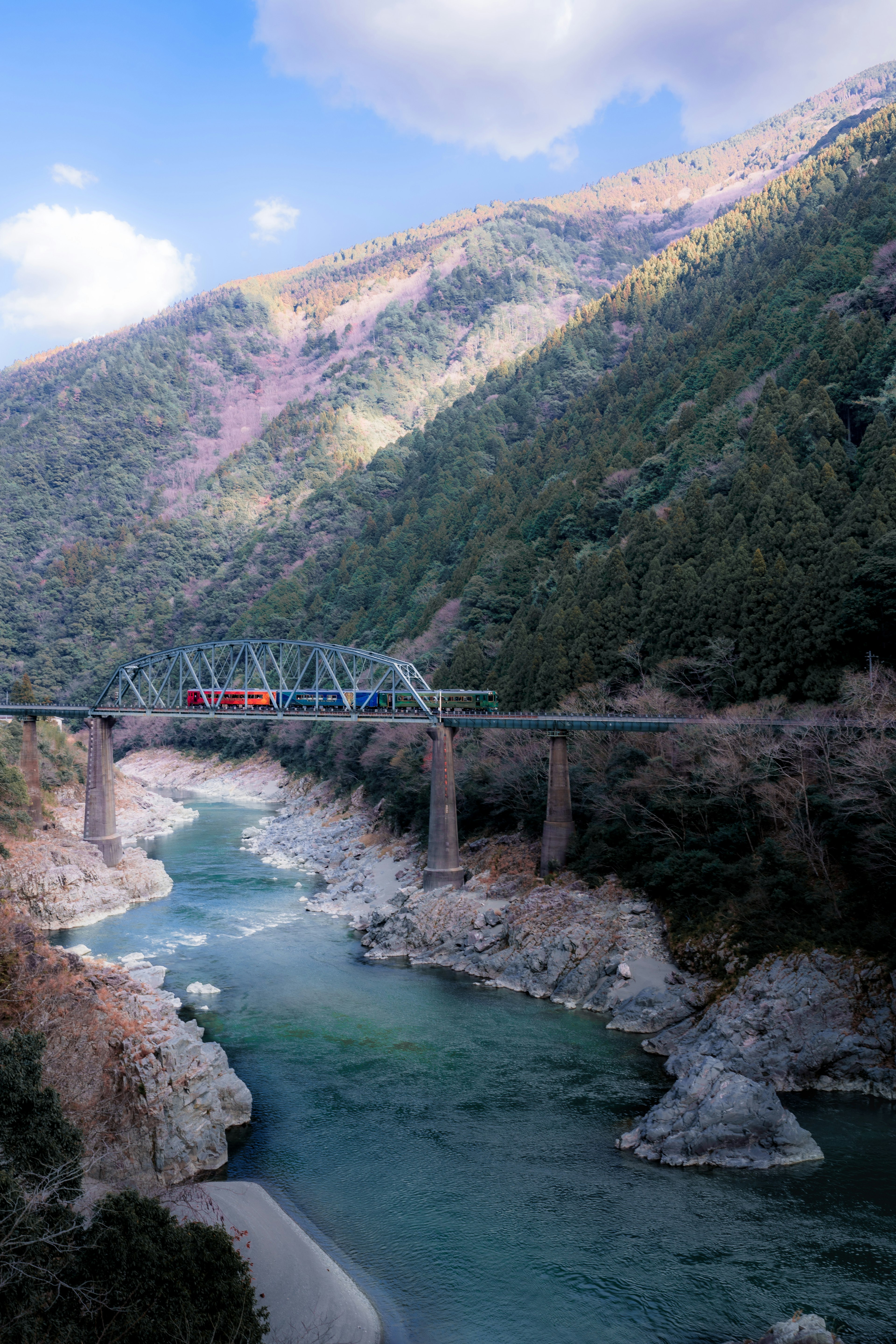 ทิวทัศน์ของสะพานรถไฟข้ามแม่น้ำที่ล้อมรอบด้วยภูเขา