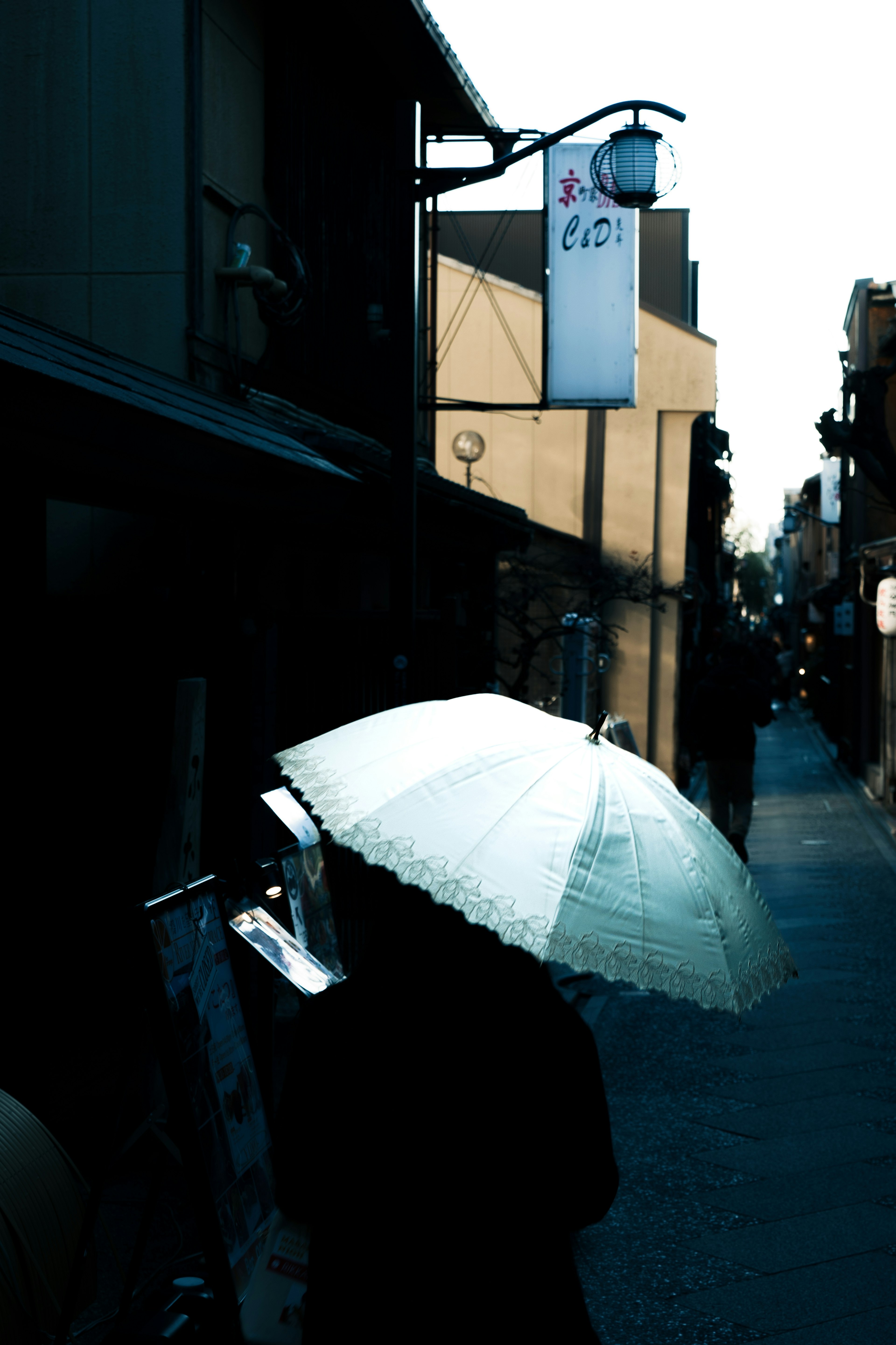 Une personne tenant un parapluie dans une ruelle sombre