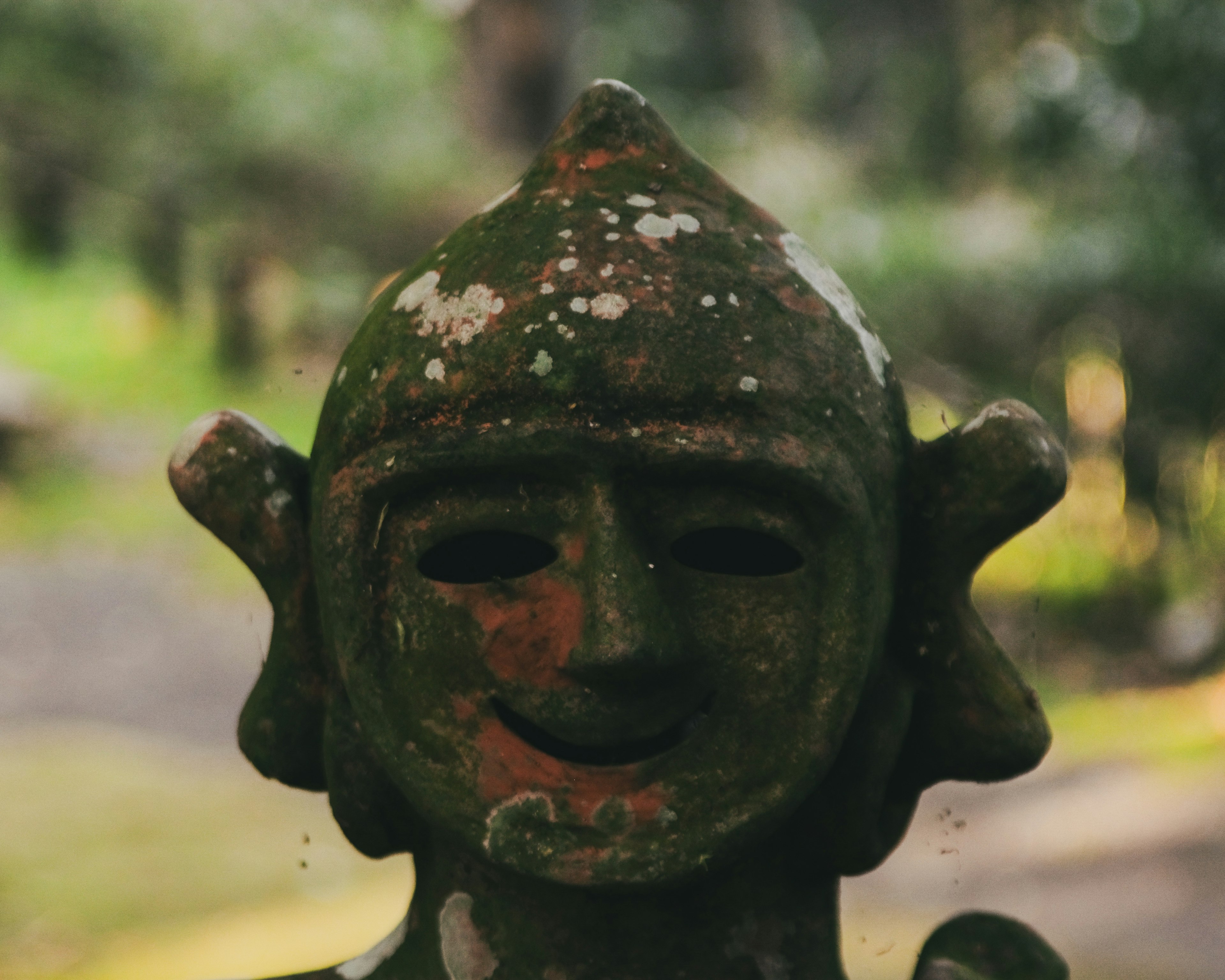 緑の背景にある笑顔の古代の石像の顔