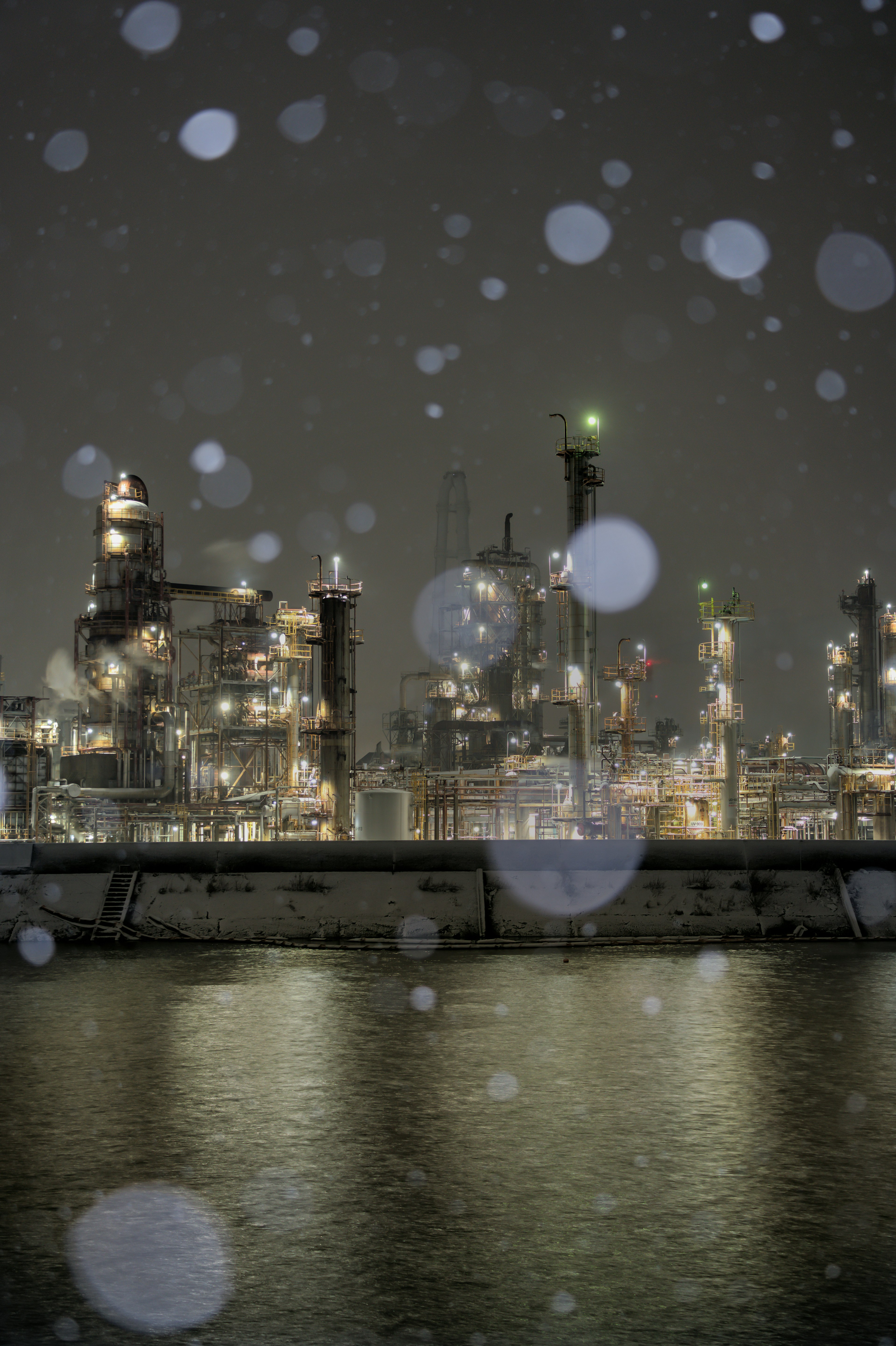 Vista nocturna de una zona industrial en la nieve con luces de fábrica brillantes