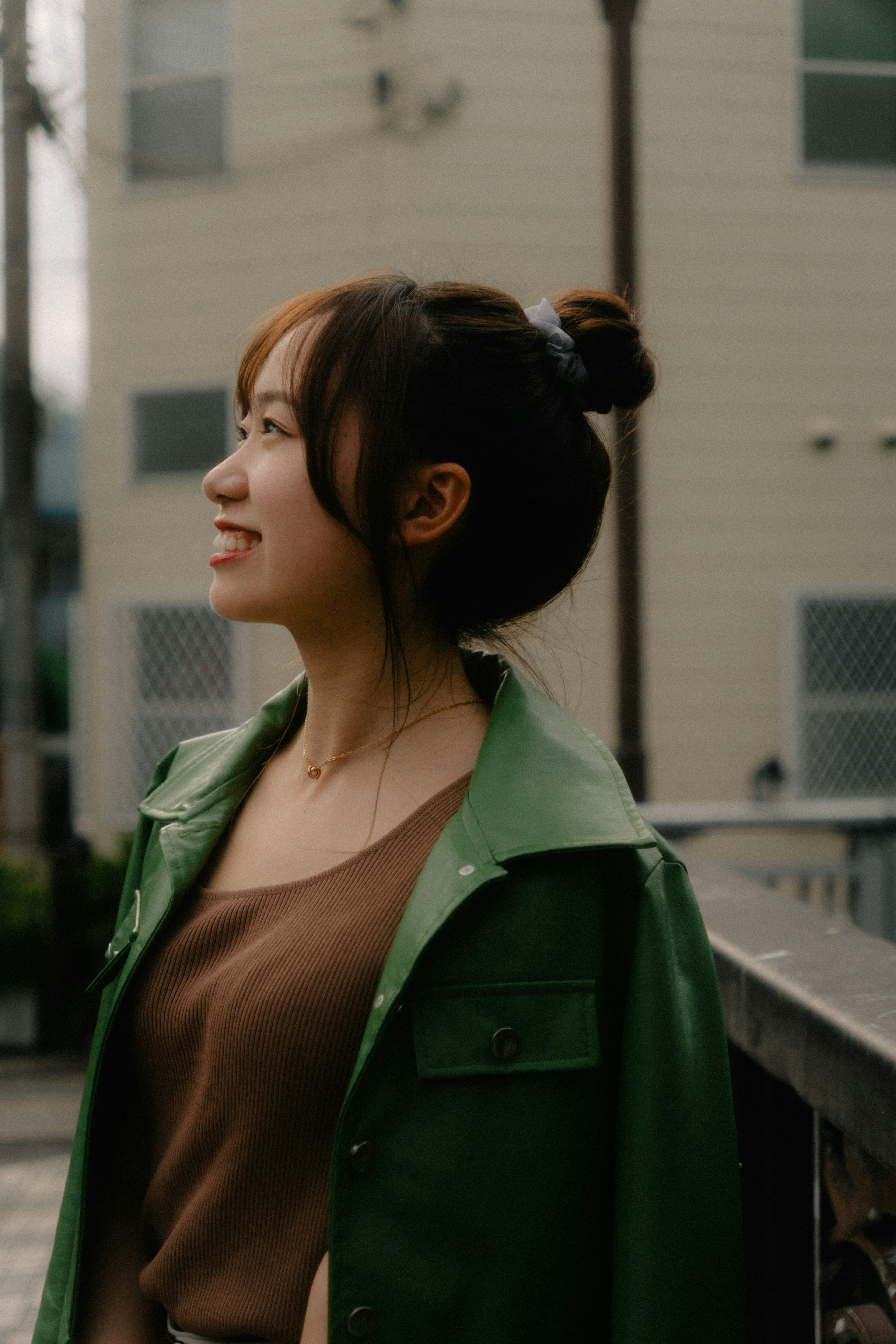 Woman in a green jacket smiling while looking to the side