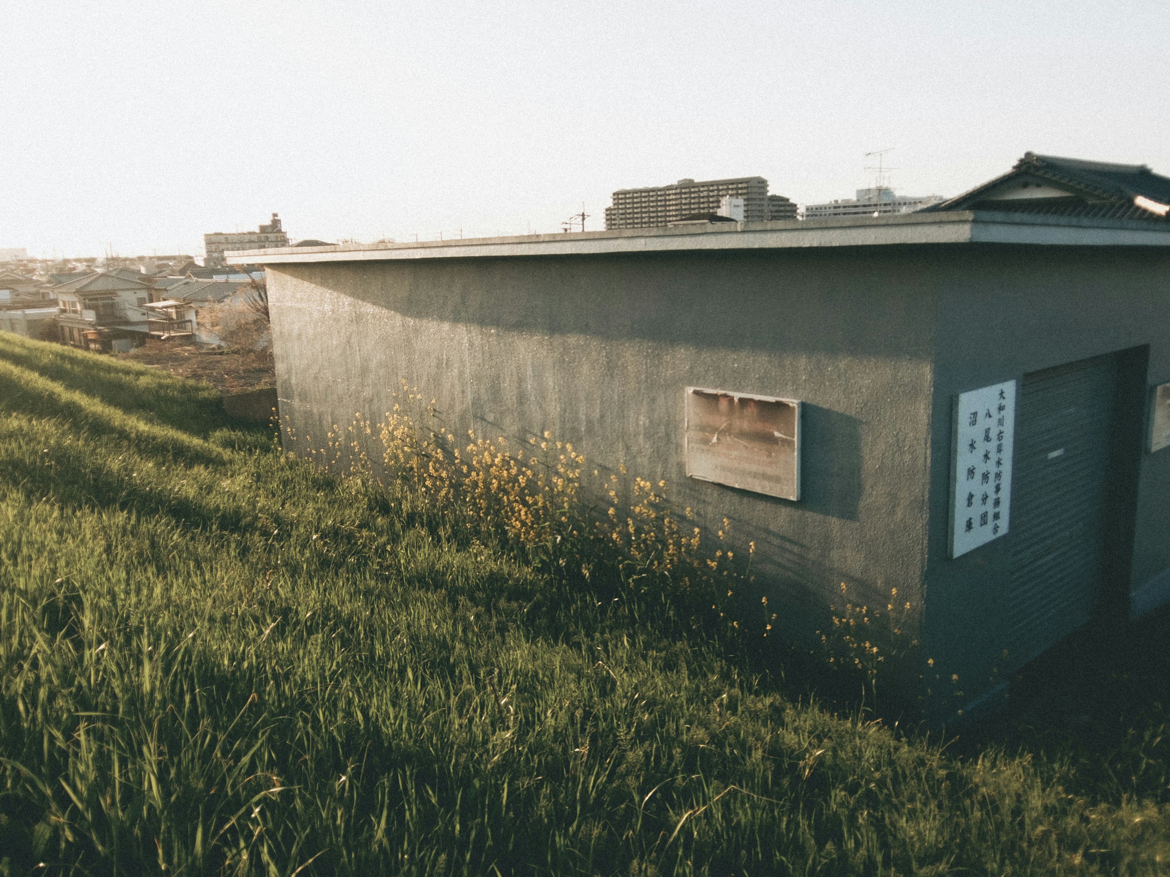 Un bâtiment en béton entouré d'herbe avec un panneau sur le mur