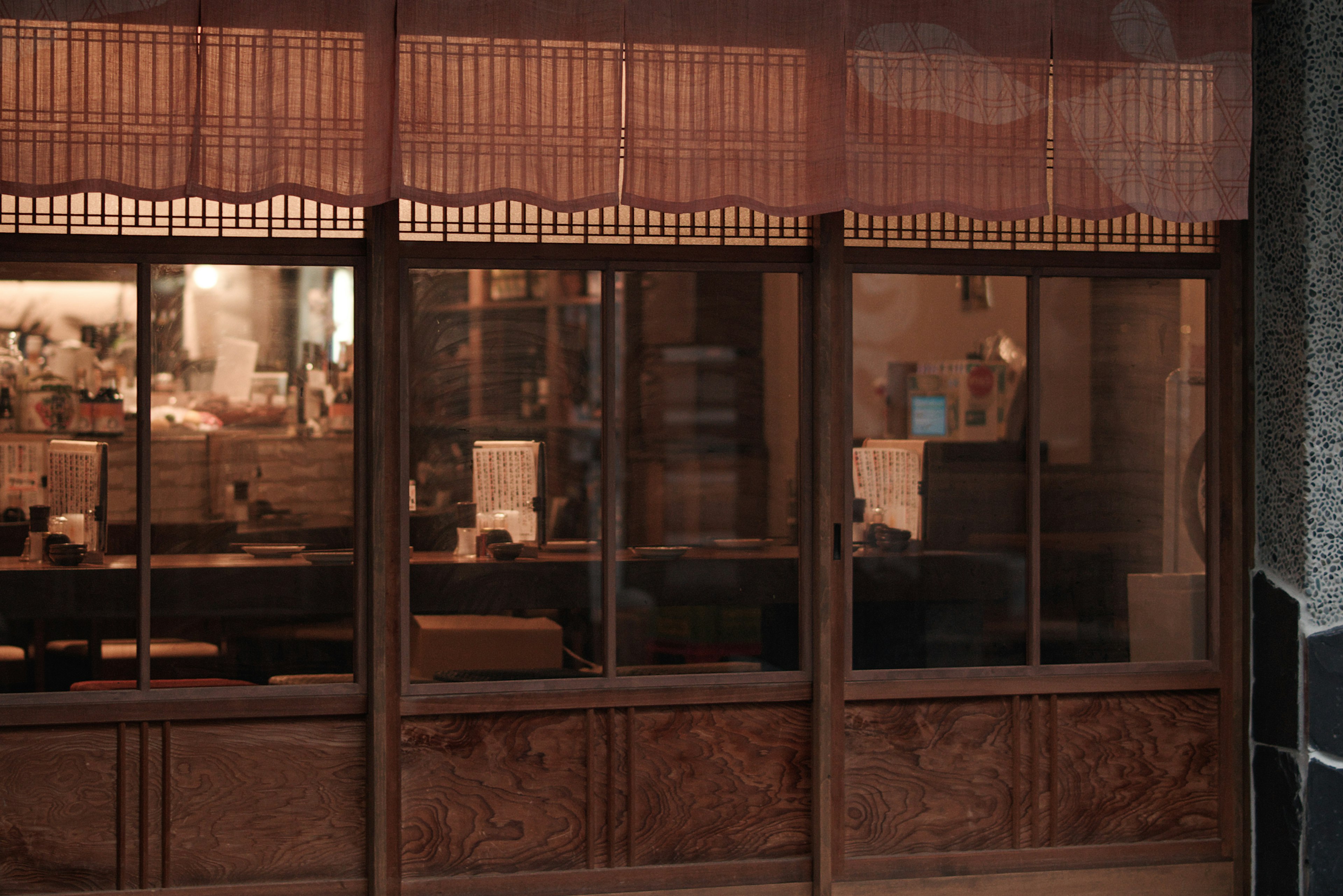 Exterior view of a shop with wooden window frames and traditional curtains