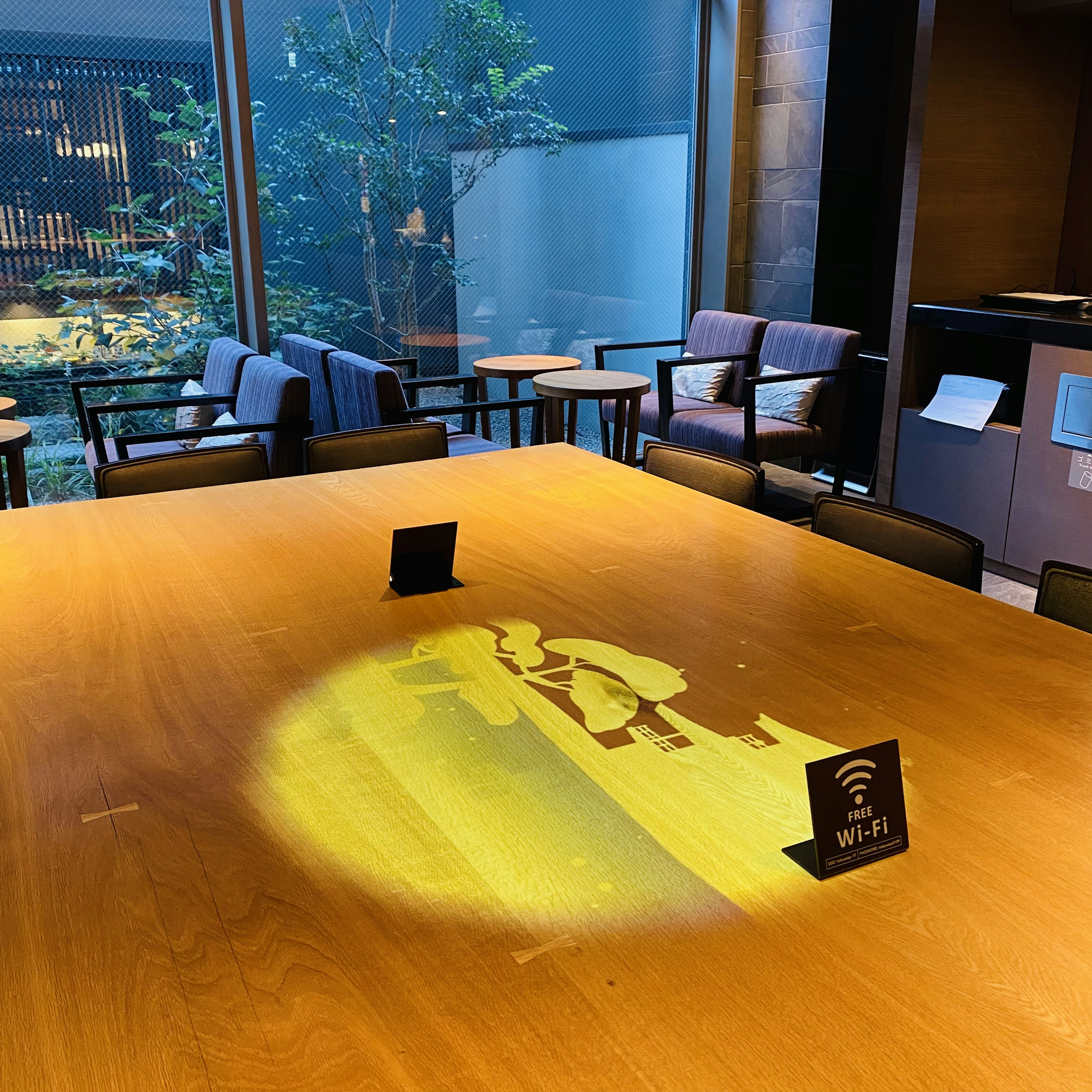 Intérieur d'un café avec une table en bois clair présentant une projection d'ombre jaune