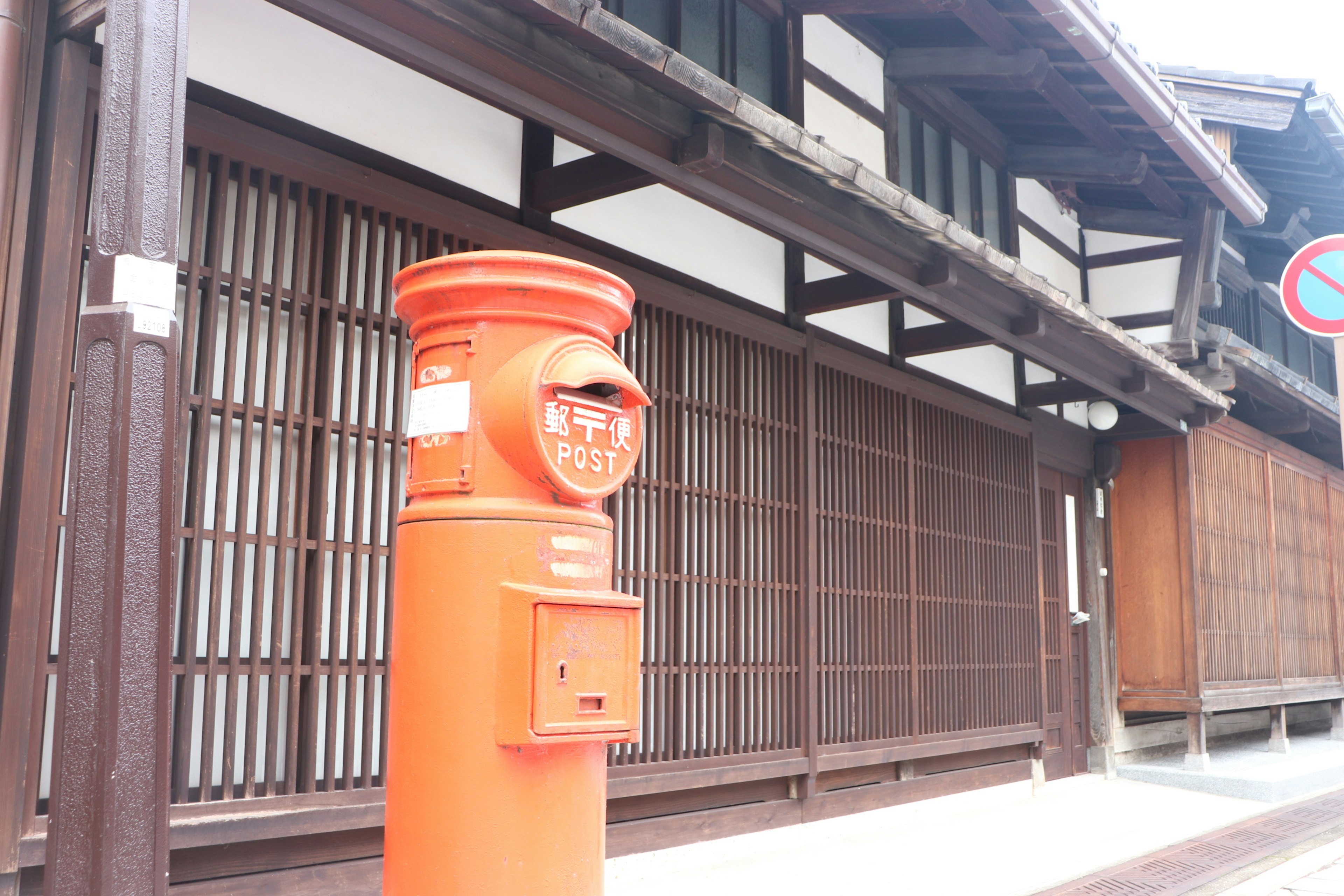 Oranger Briefkasten vor einem traditionellen japanischen Haus