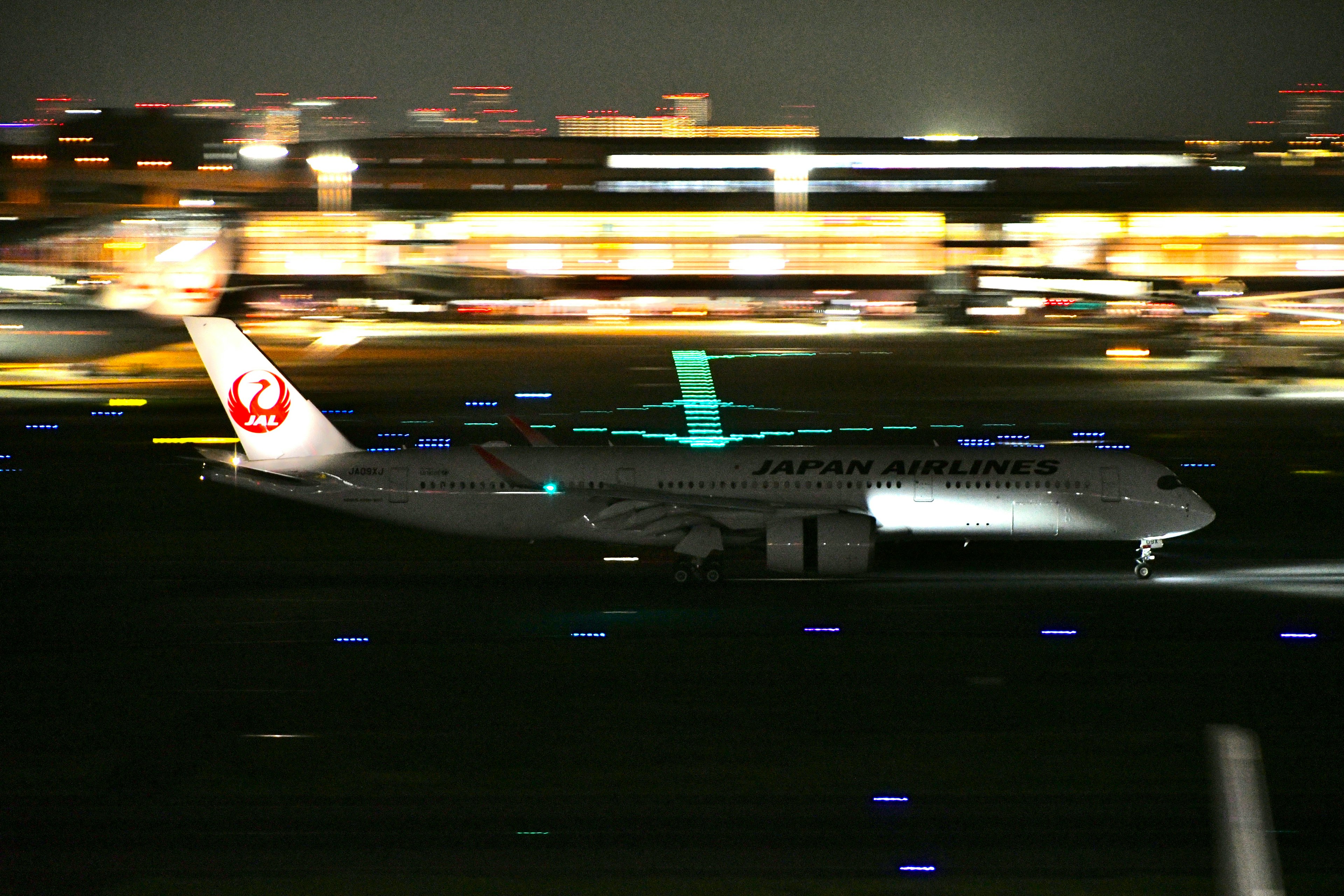 夜間の空港で滑走路を走行する日本航空の飛行機