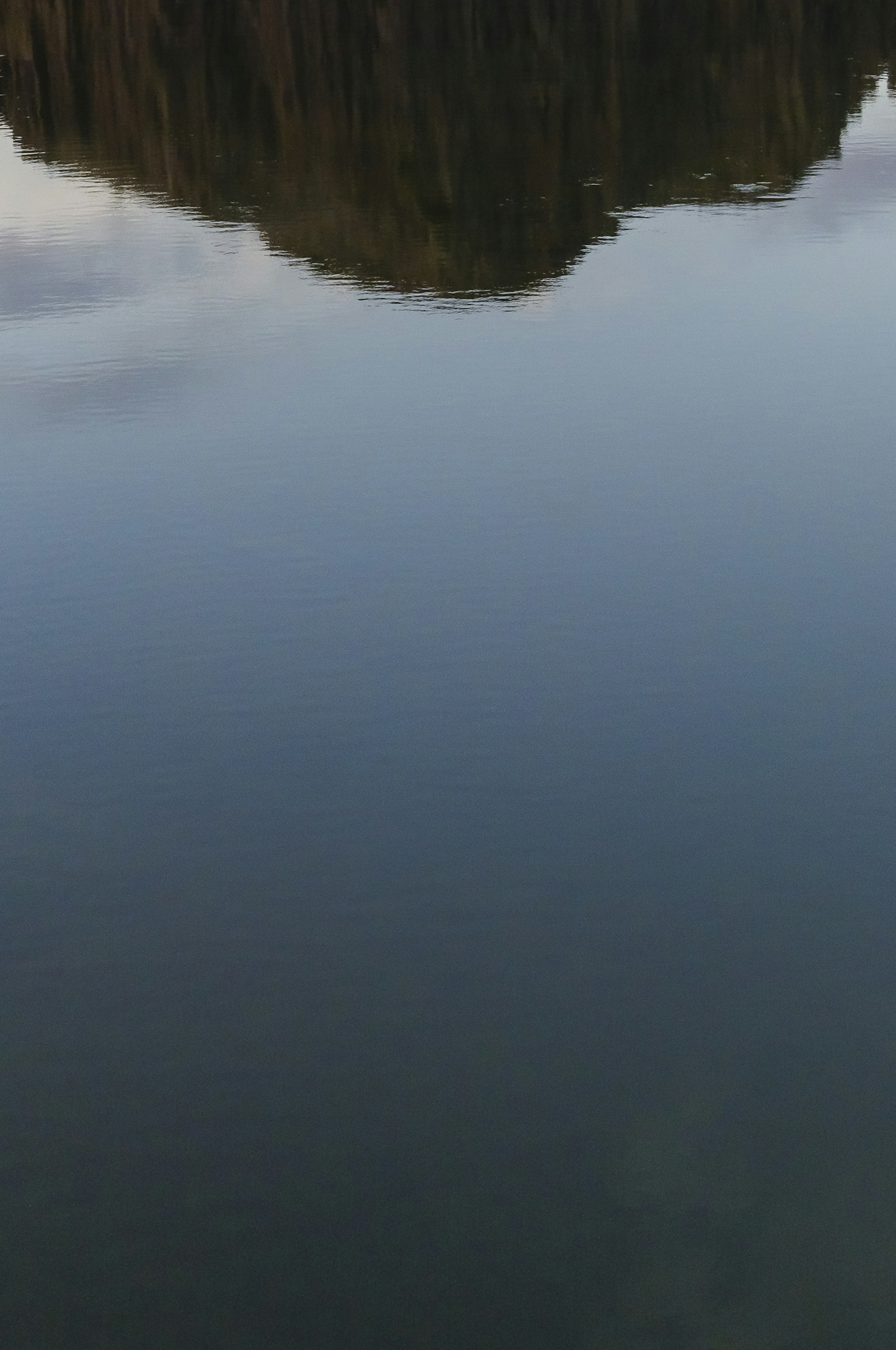 Danau tenang mencerminkan pemandangan pegunungan