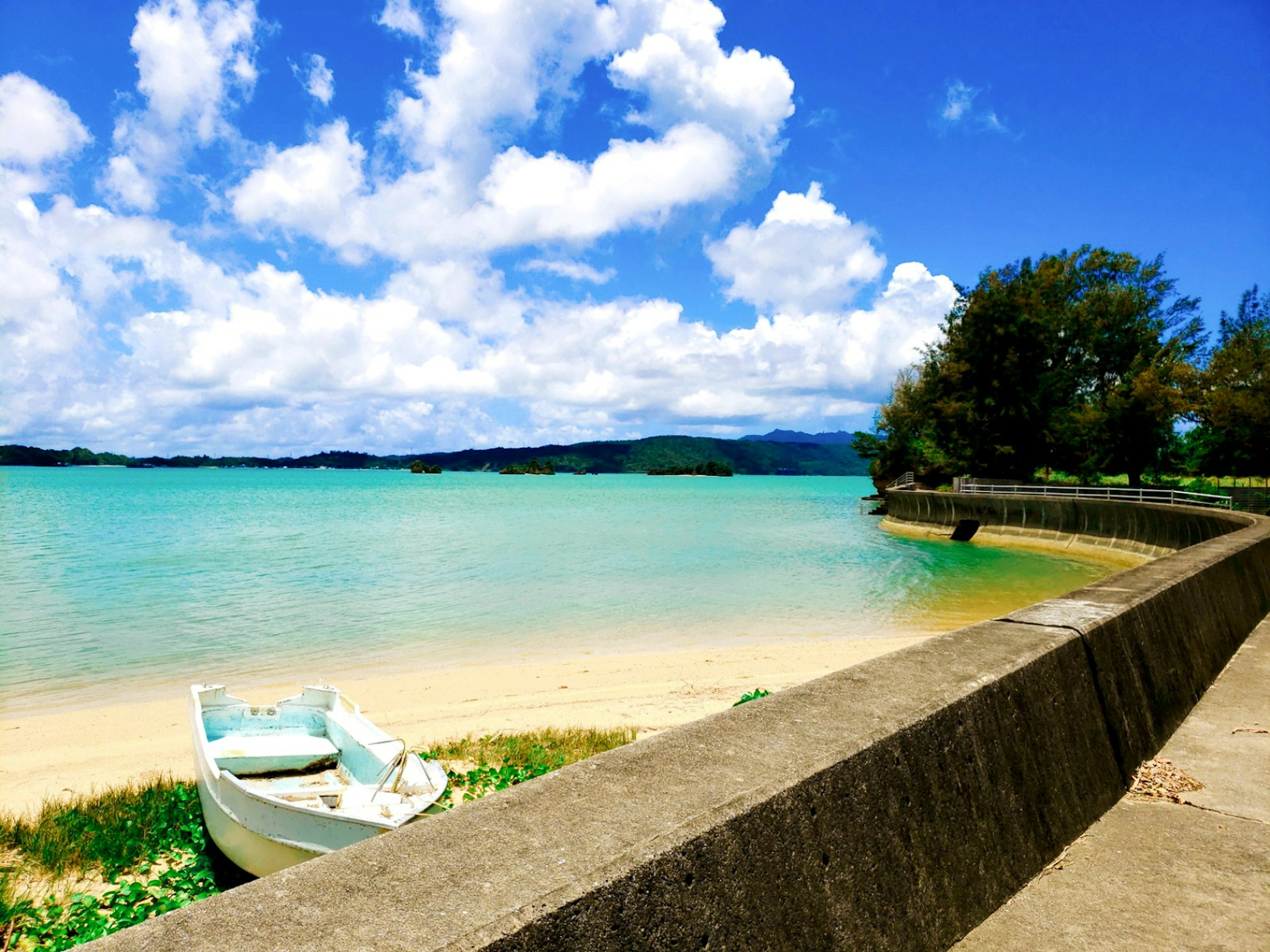 Vue de plage pittoresque avec de l'eau turquoise et des nuages moelleux un bateau reposant sur le rivage