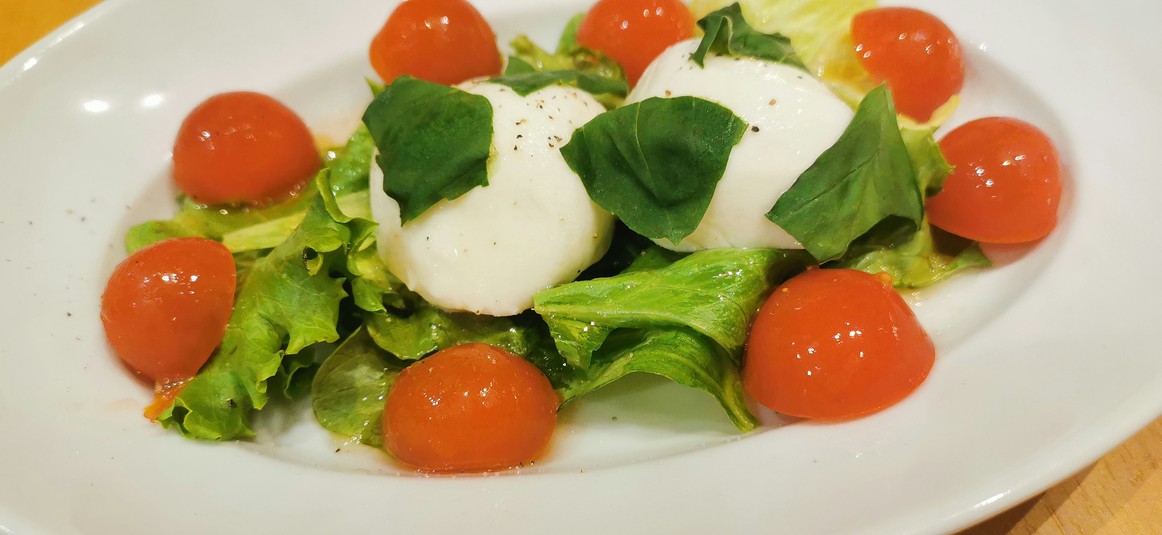 Fresh salad topped with mozzarella cheese and basil leaves