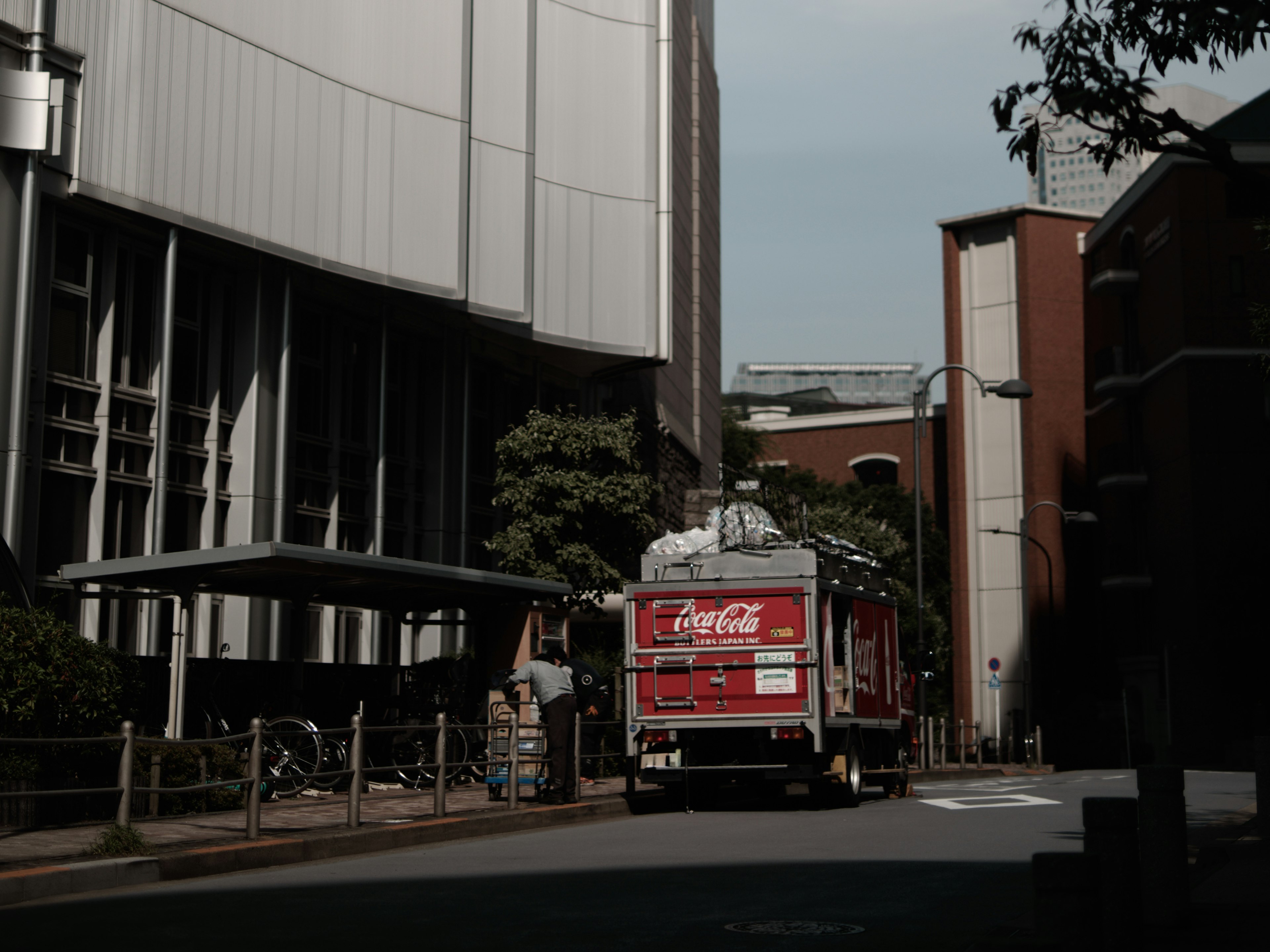 Coca-Cola truck parked on a street surrounded by buildings and trees