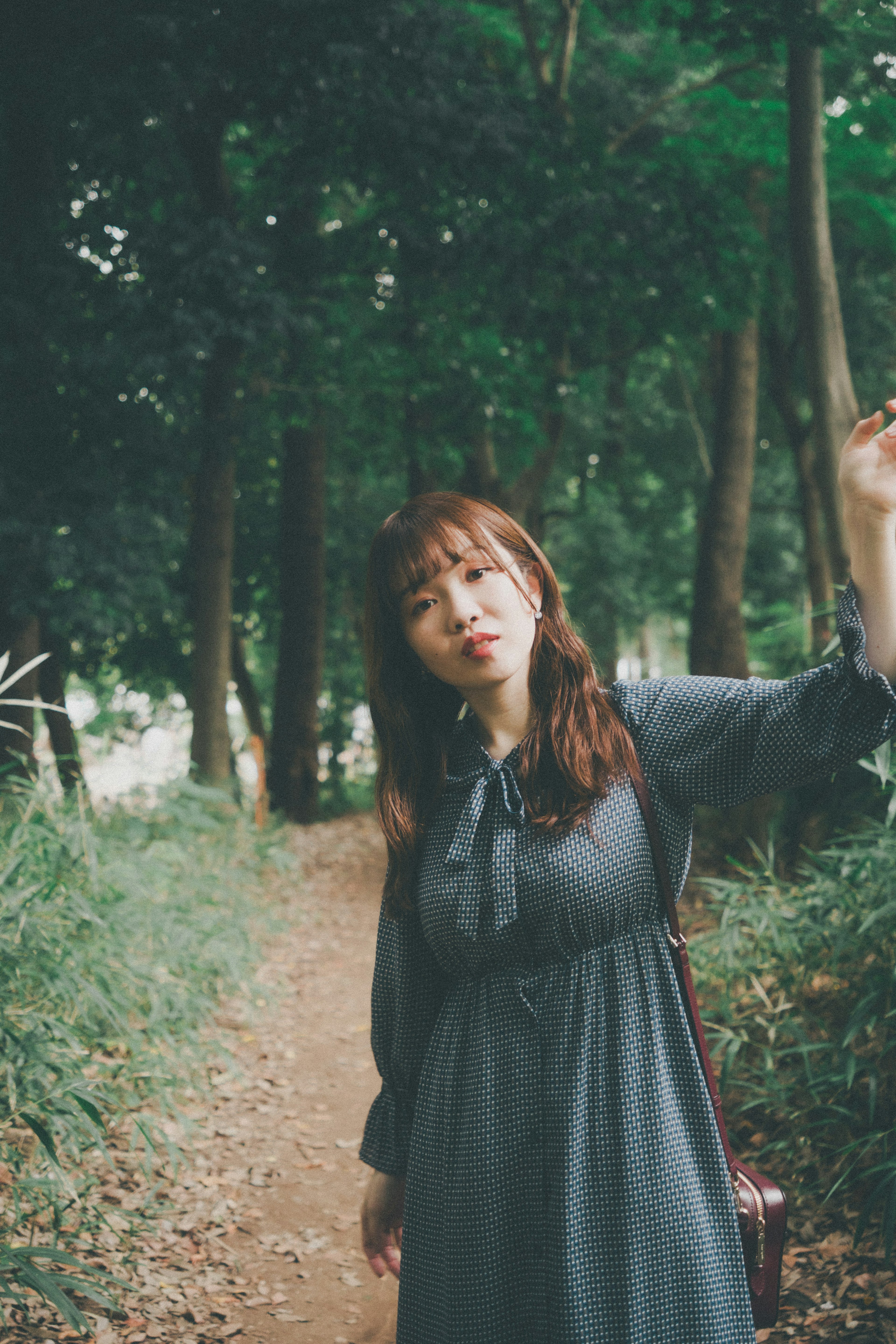 Woman posing on a path surrounded by green trees