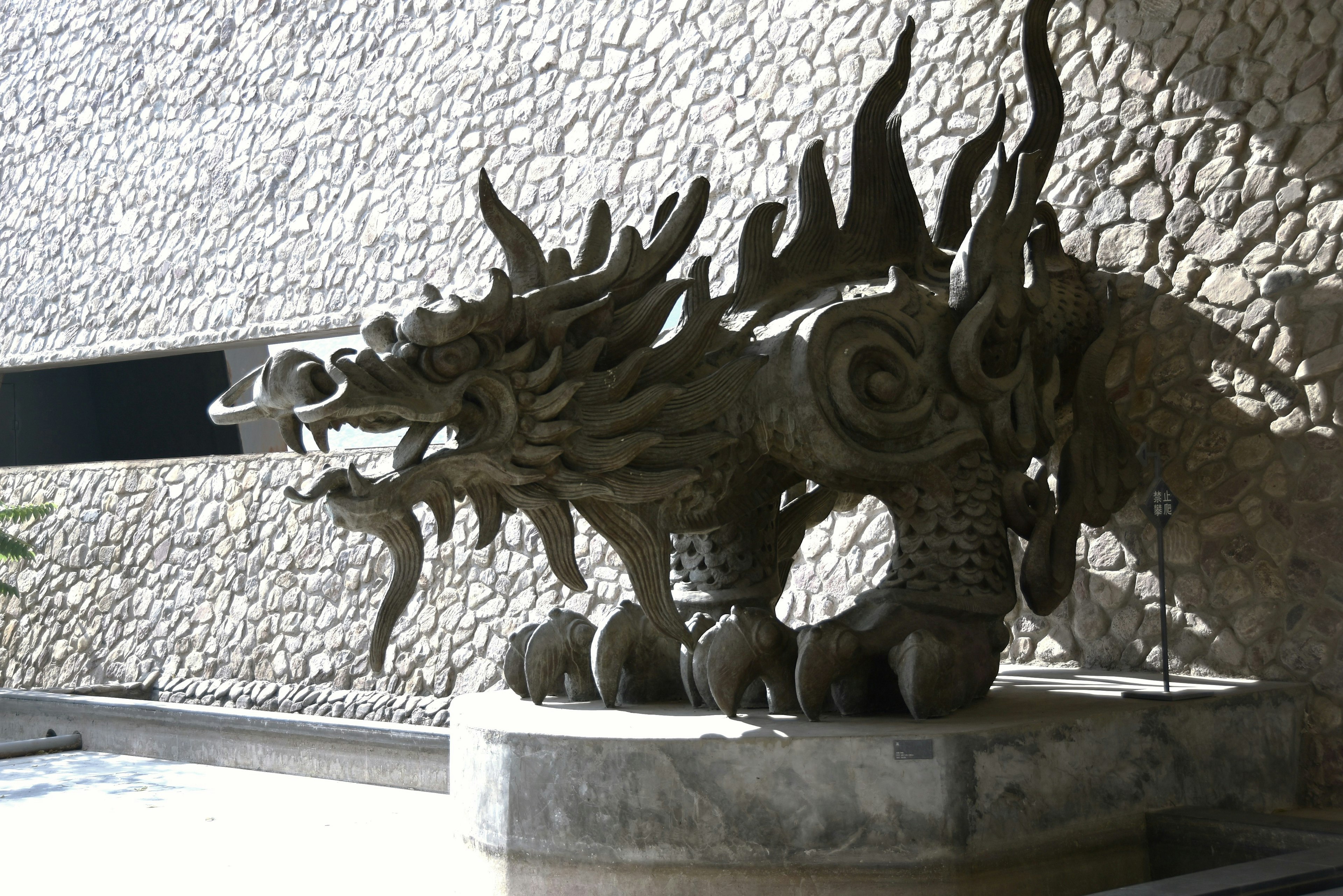 A dragon sculpture positioned in front of a textured stone wall