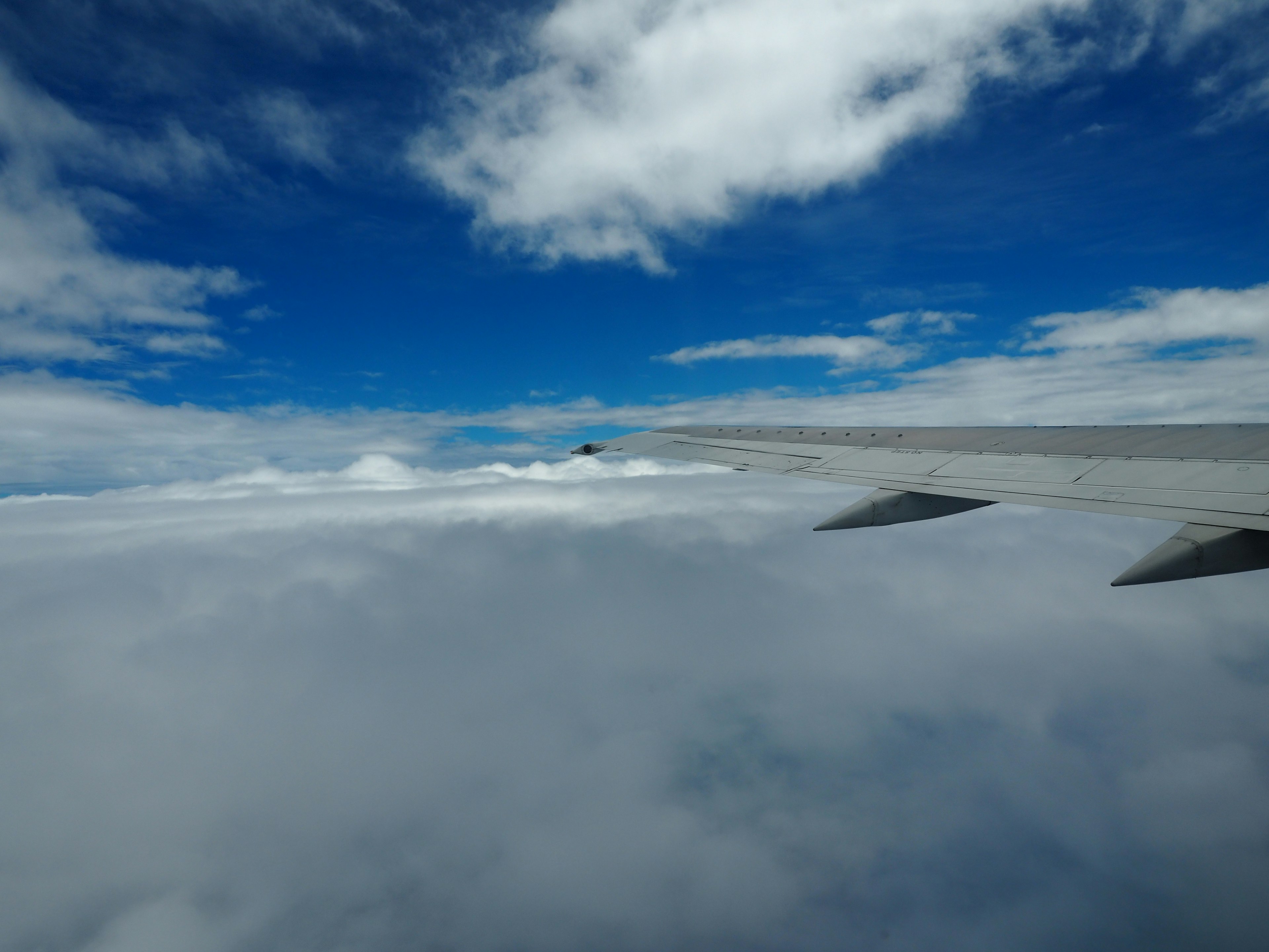 Langit biru dengan awan putih terlihat dari sayap pesawat