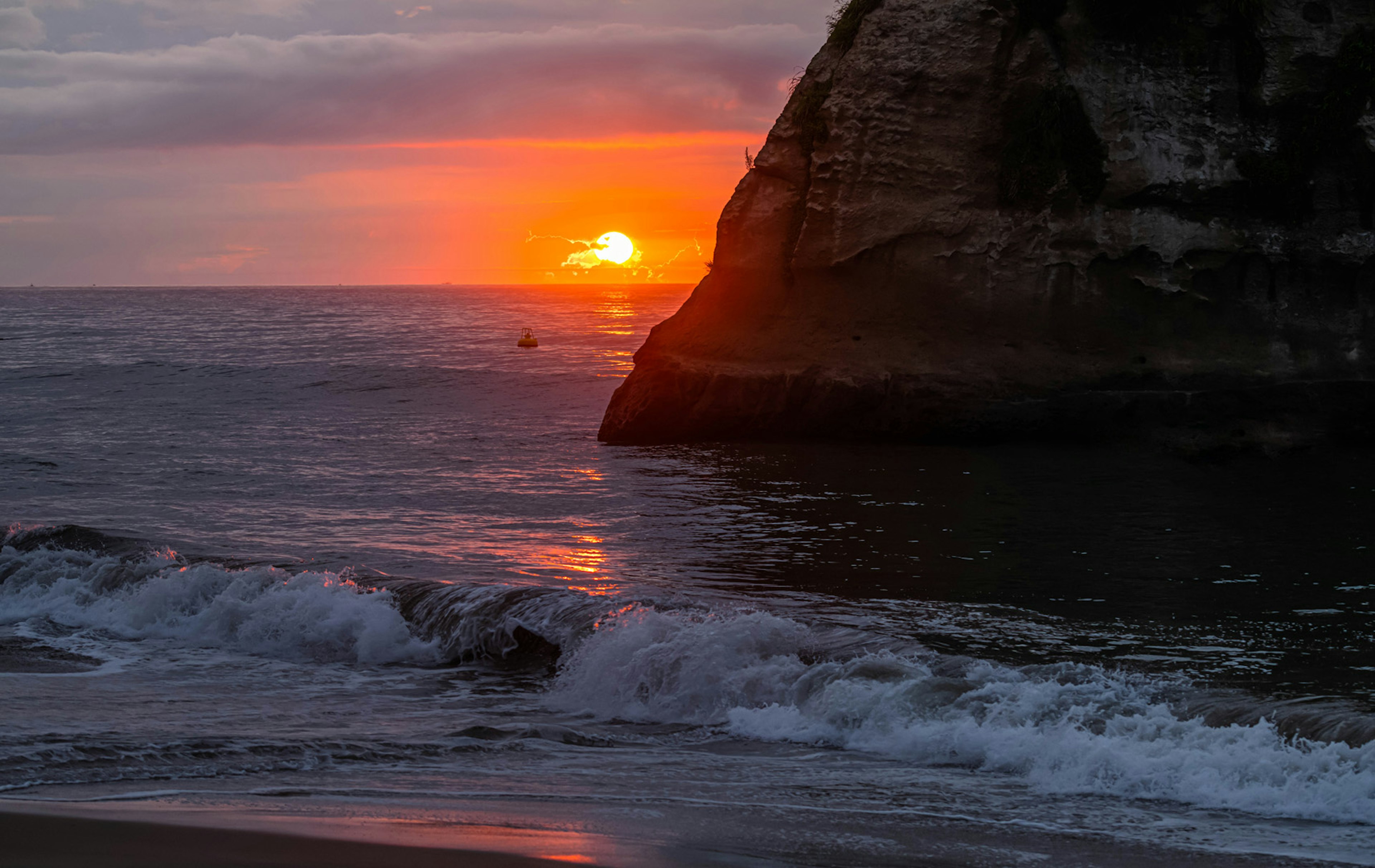 Hermoso atardecer sobre el océano con silueta de la costa y rocas