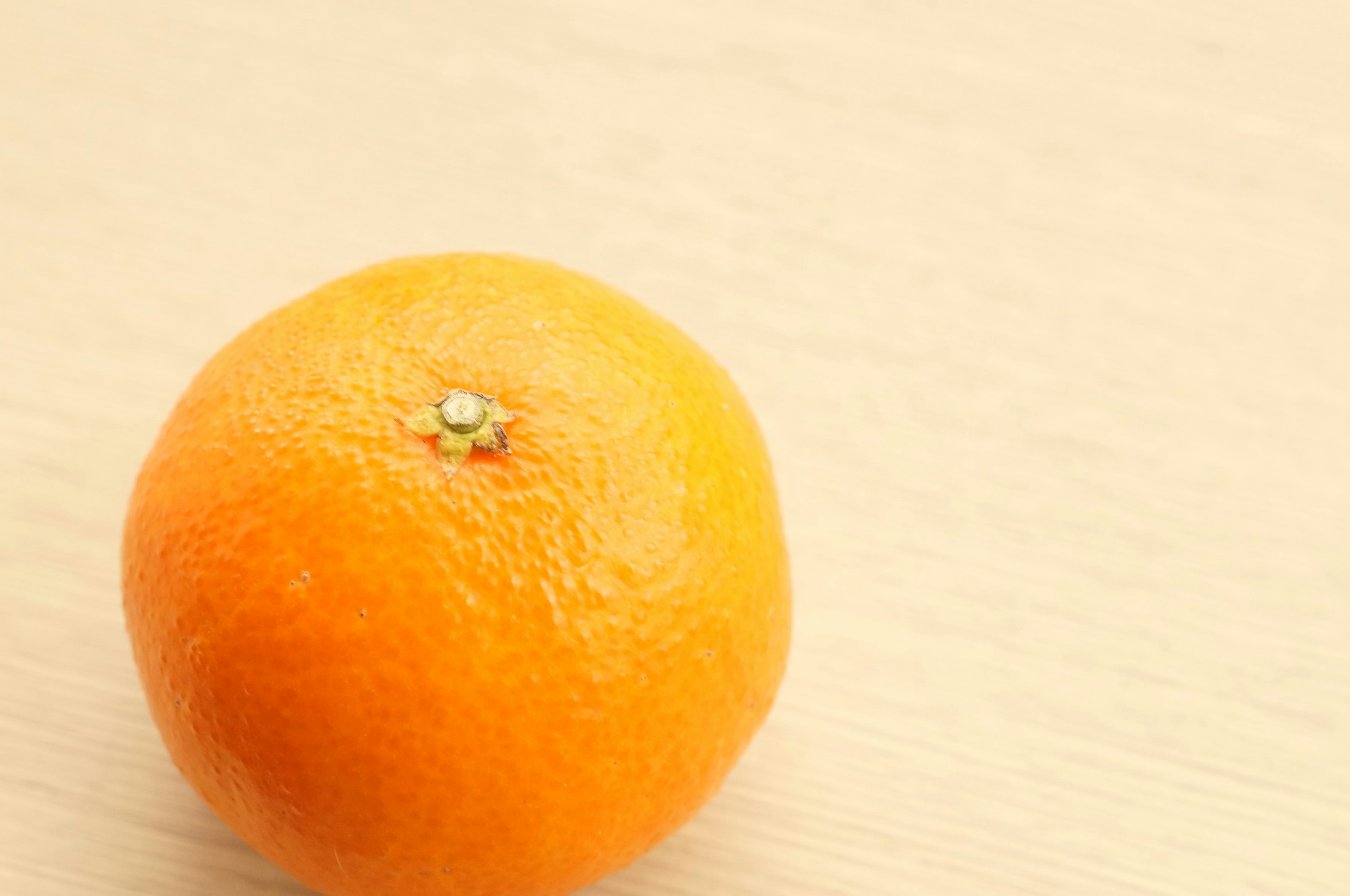 A bright orange fruit on a light wooden surface