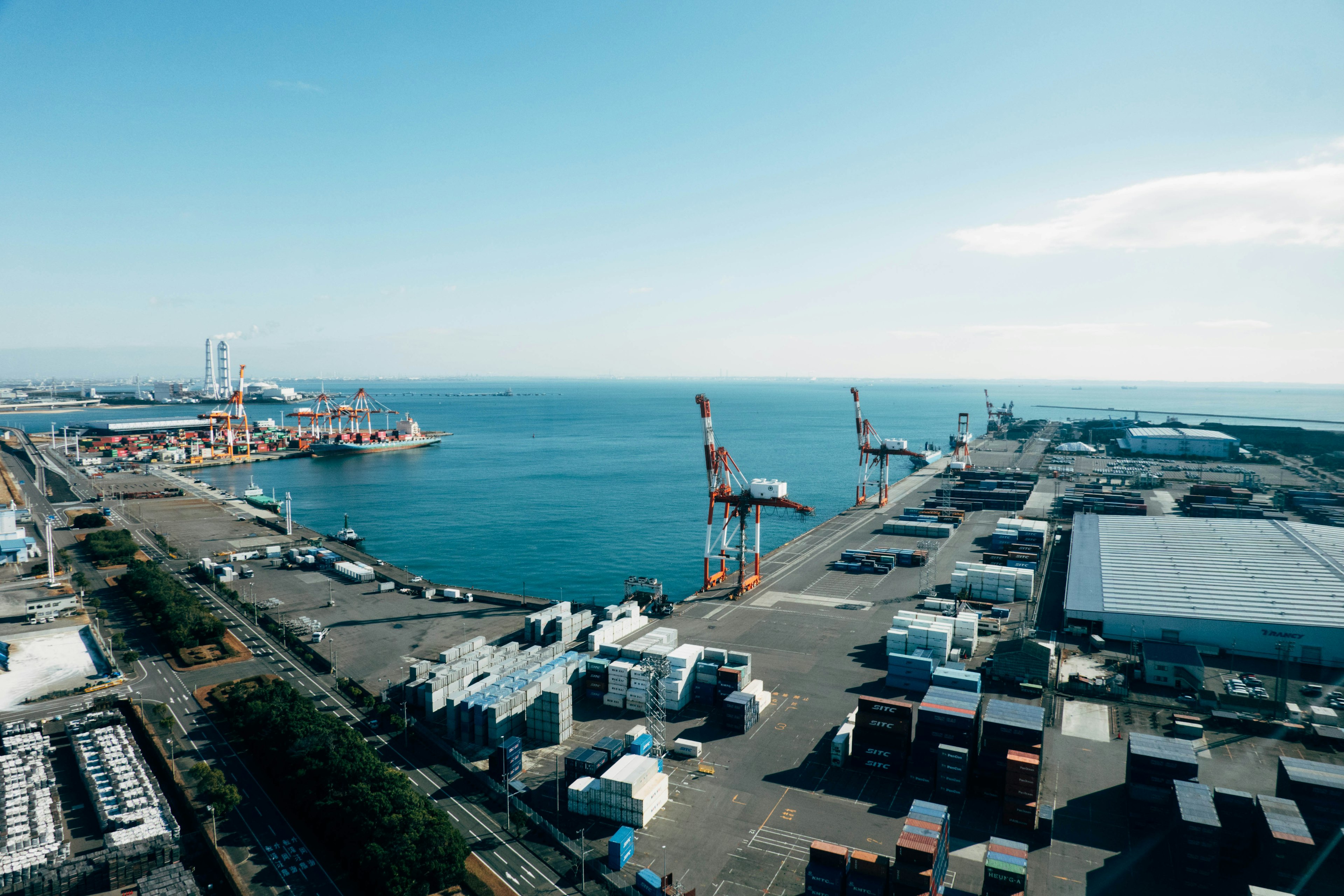 Vue aérienne d'un port avec des grues et une mer bleue