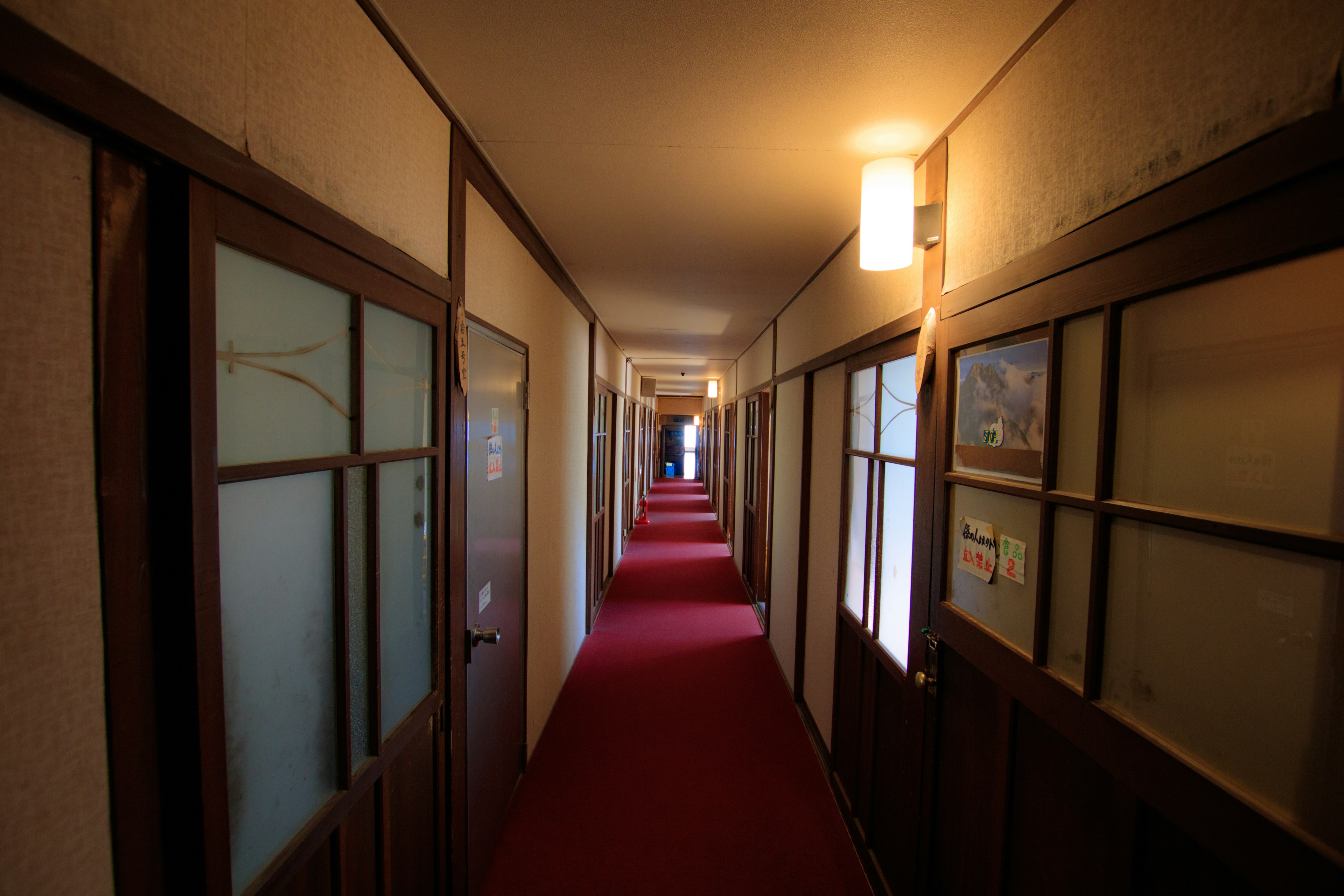 Long hallway with red carpet and wooden doors in a Japanese inn