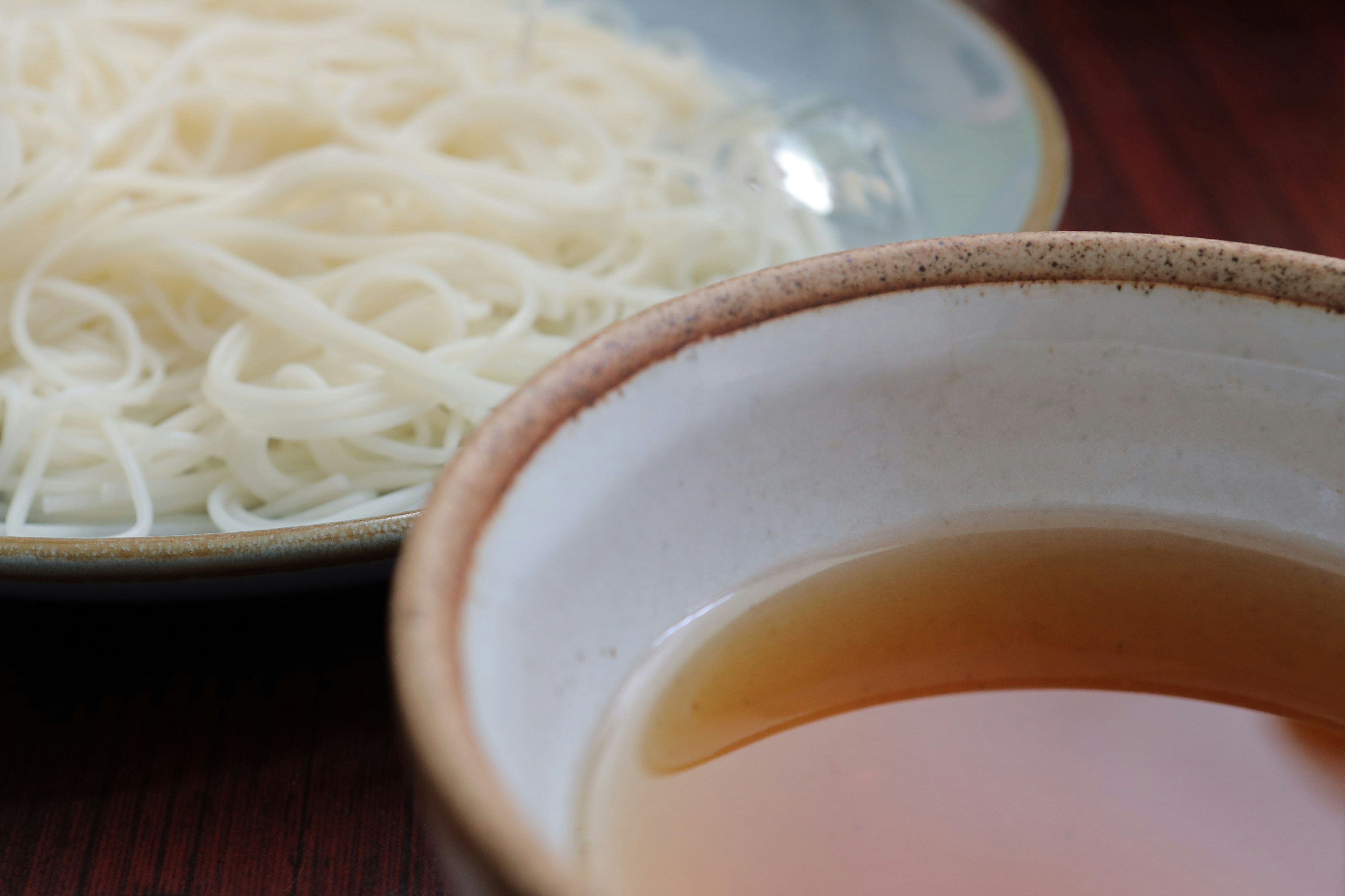 Un bol de sauce brune à côté d'une assiette de nouilles blanches