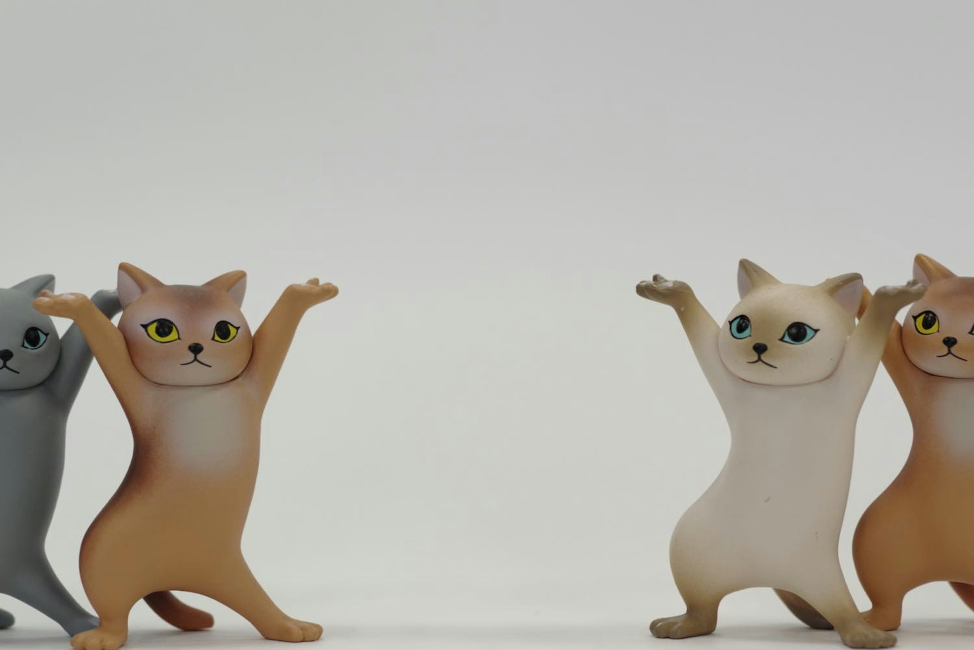 Two cat figurines with raised hands in a playful pose