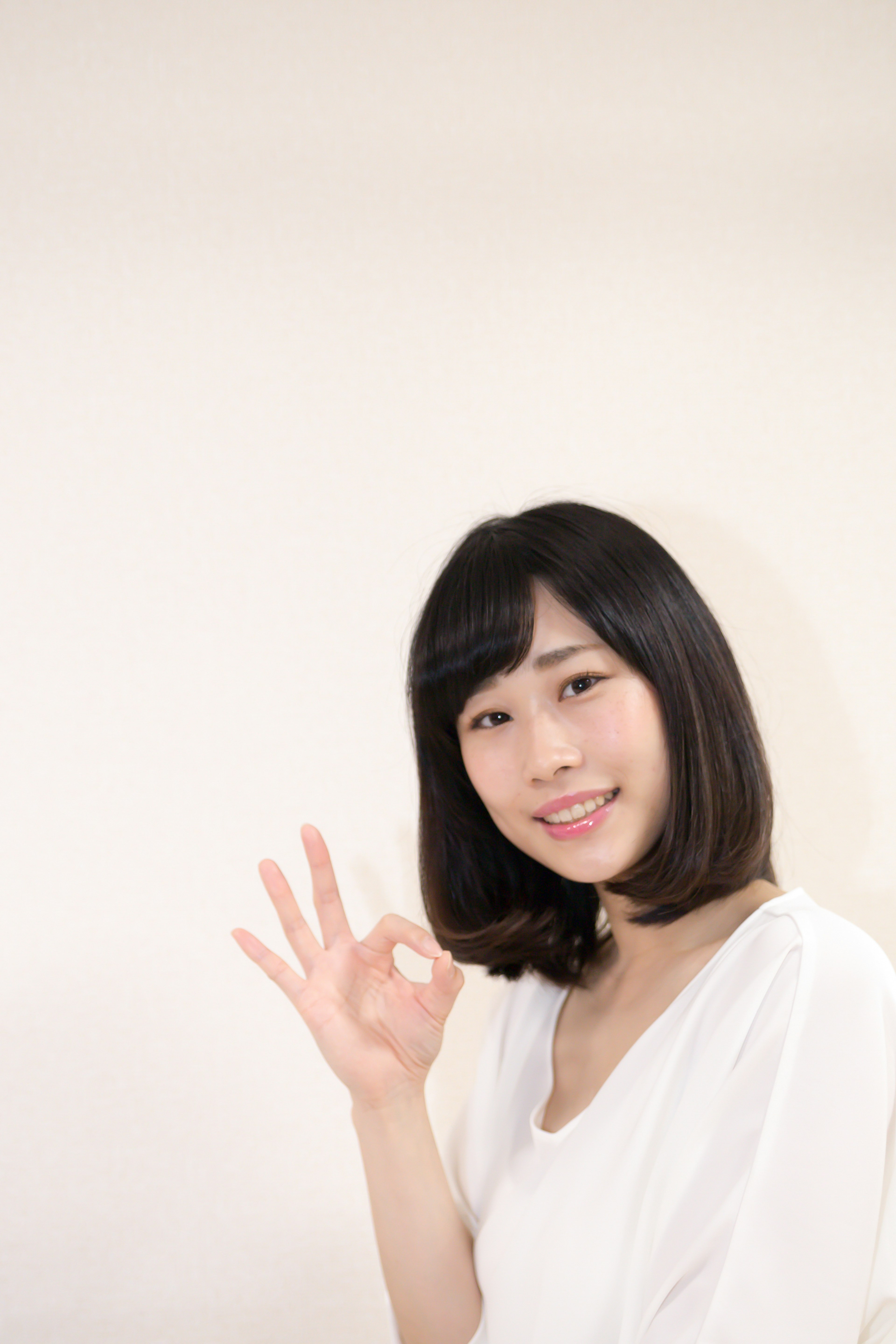 Woman smiling and making an OK sign against a white background